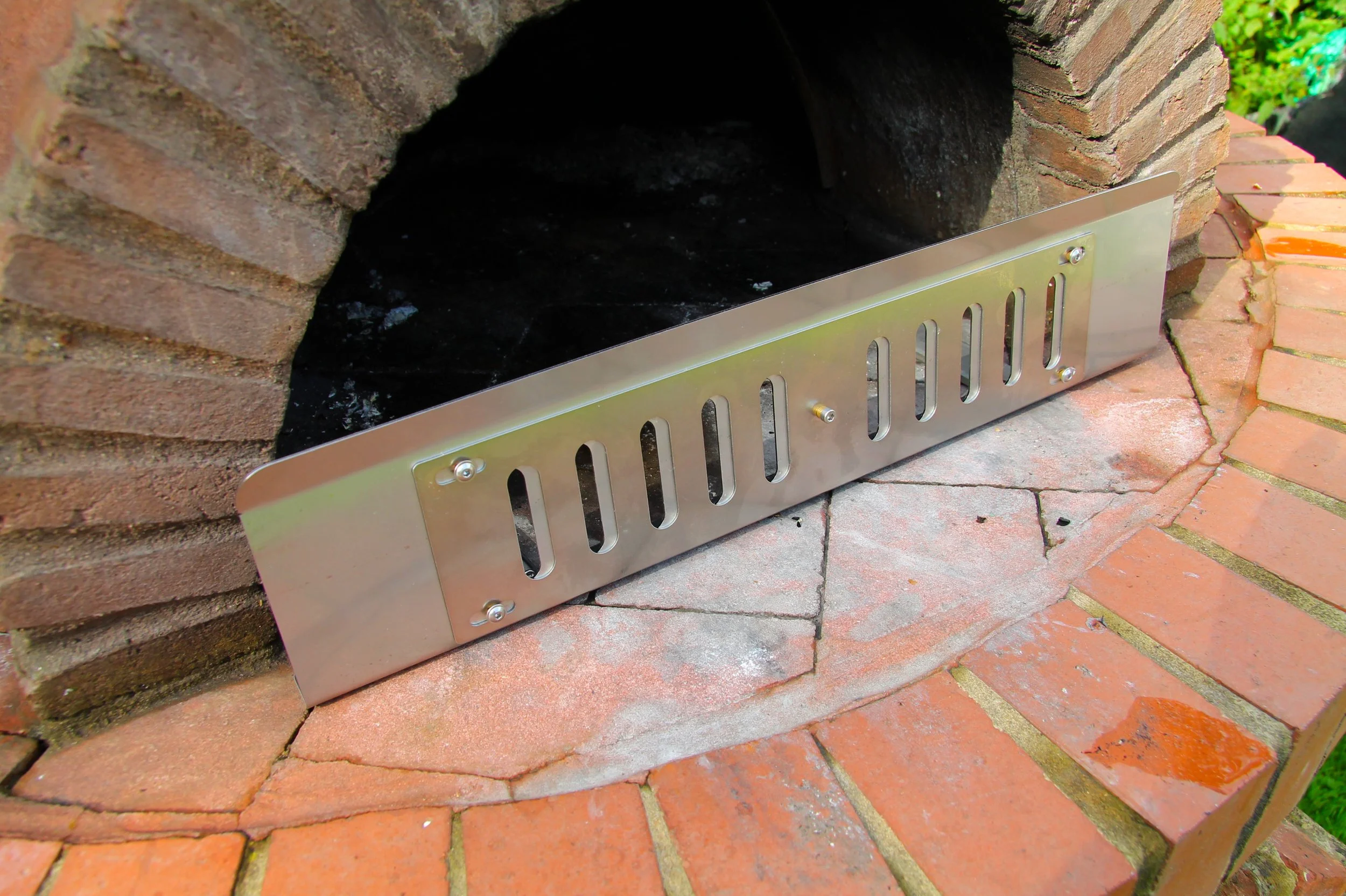 adjustable fire guard in front of a pizza oven wfo