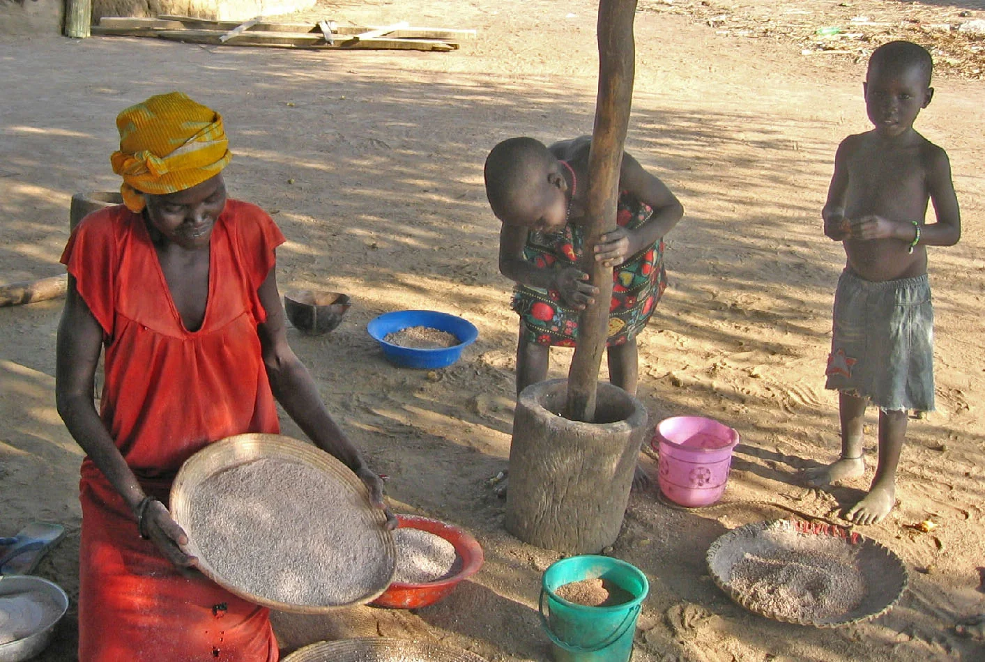 A mother and her children pound millet in South Sudan