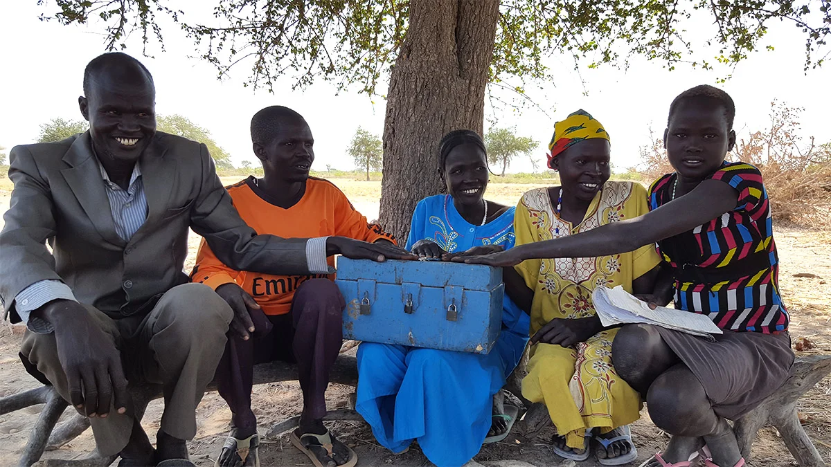 Above: Members of a Savings Group in Warrap State pose with their savings box after recording their weekly contributions. The keys to the three locks are held by different members chosen by their group.