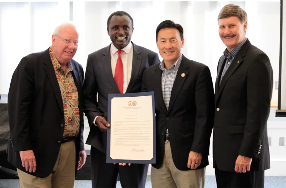 Five Talents Board Chairman, Jim Oakes, and Executive Director, Dale Stanton-Hoyle, receive a resolution from Virginia Delegate Mark Keam with Program Partner, Harun Mutuma.