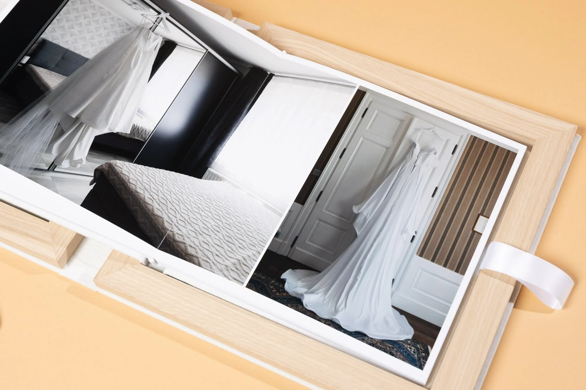 A mirror reflecting a bedroom with white curtains, a textured white bedspread, a black wardrobe, a door, and decorative wall panels.