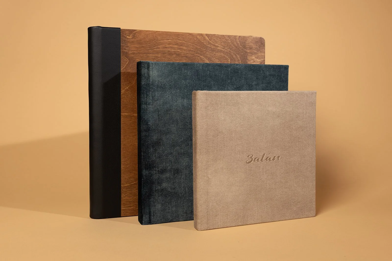 Three hardcover books standing upright on a beige background, with the smallest book in front and the largest behind. The smallest book has the word 'Zalán' written on its cover.