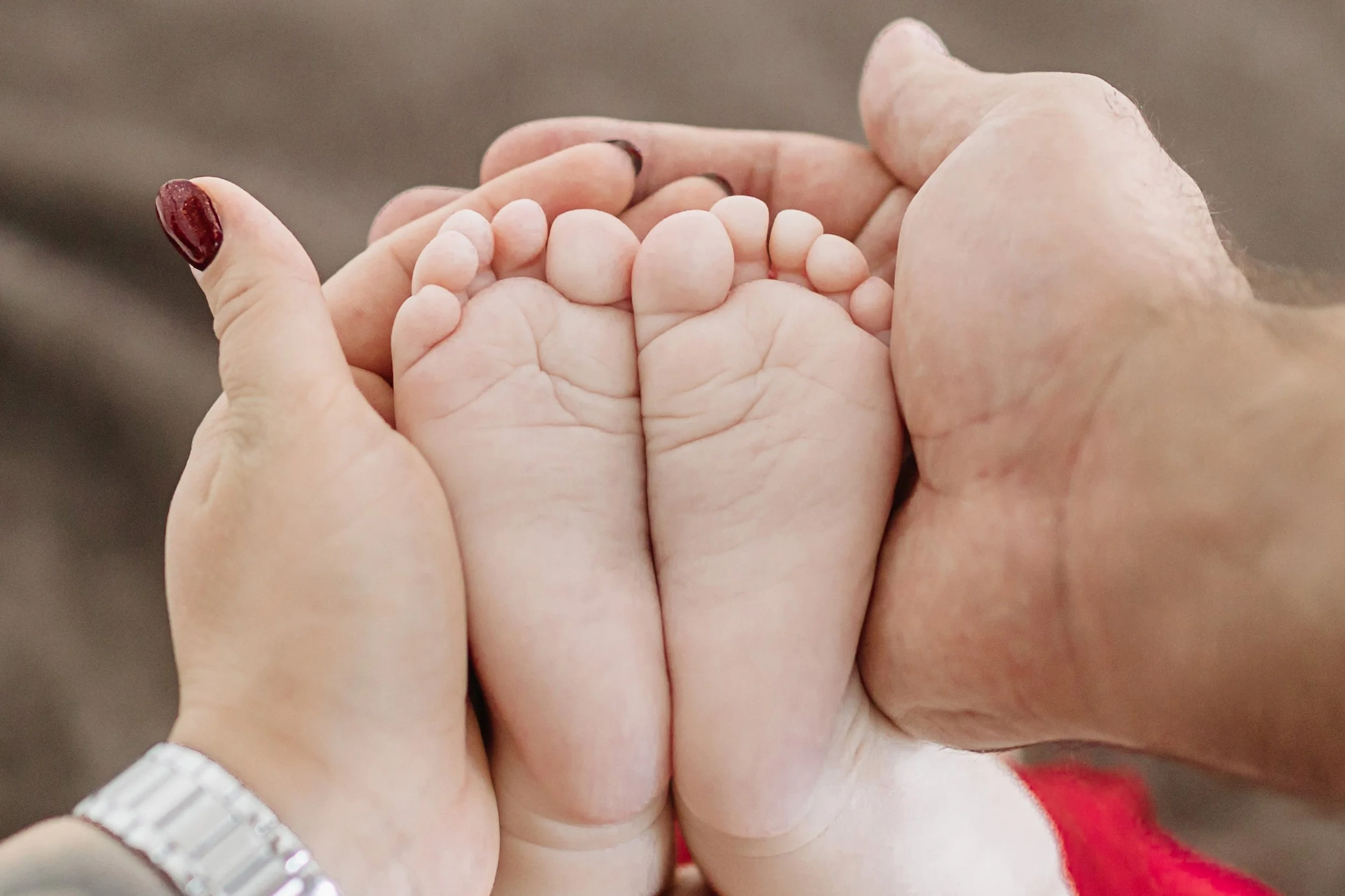 Close-up of an adult holding a child's hand, emphasizing the size difference, with a focus on the hands and fingers.
