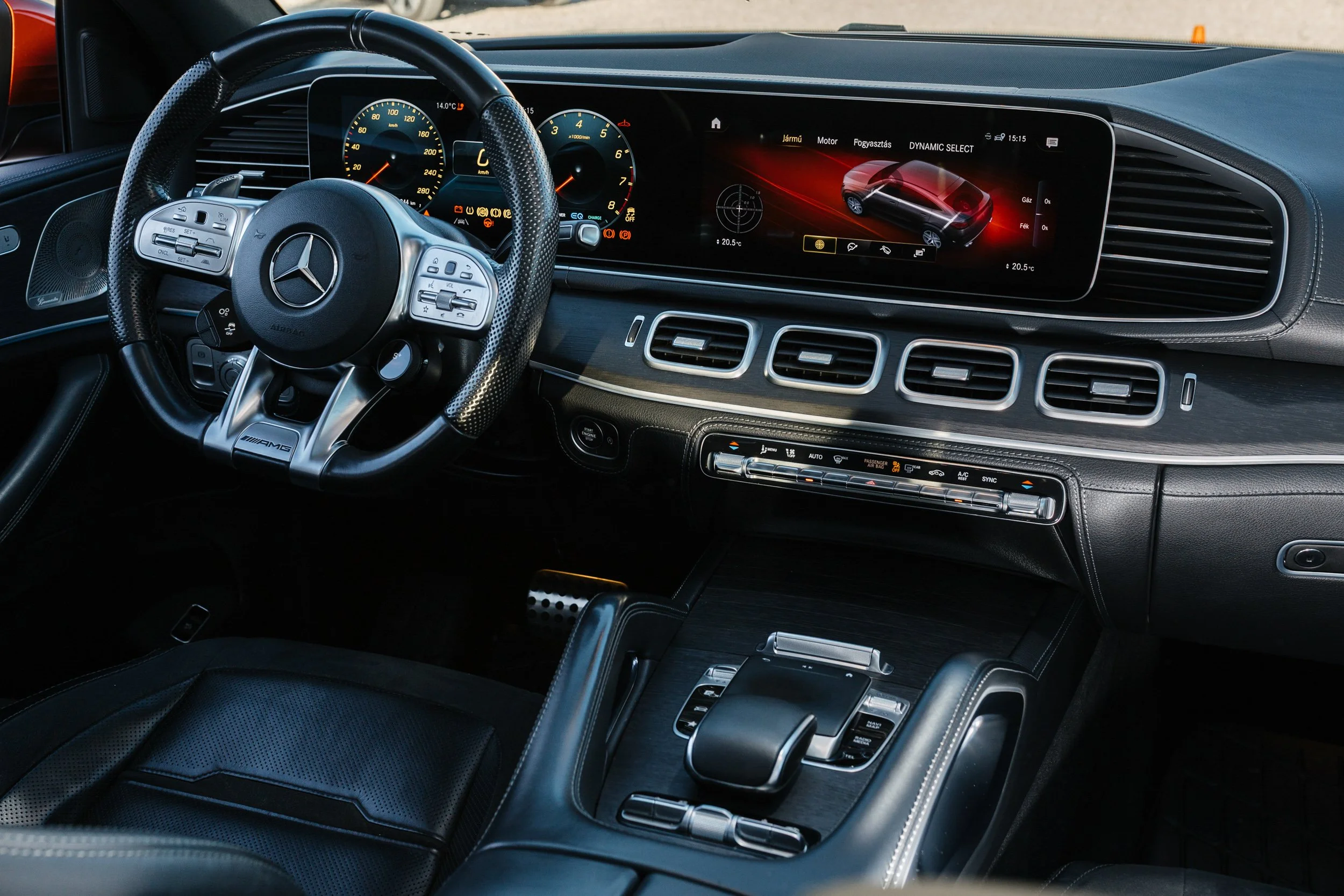 Interior of a luxury Mercedes-Benz vehicle showing the steering wheel, digital instrument cluster, and infotainment screen.