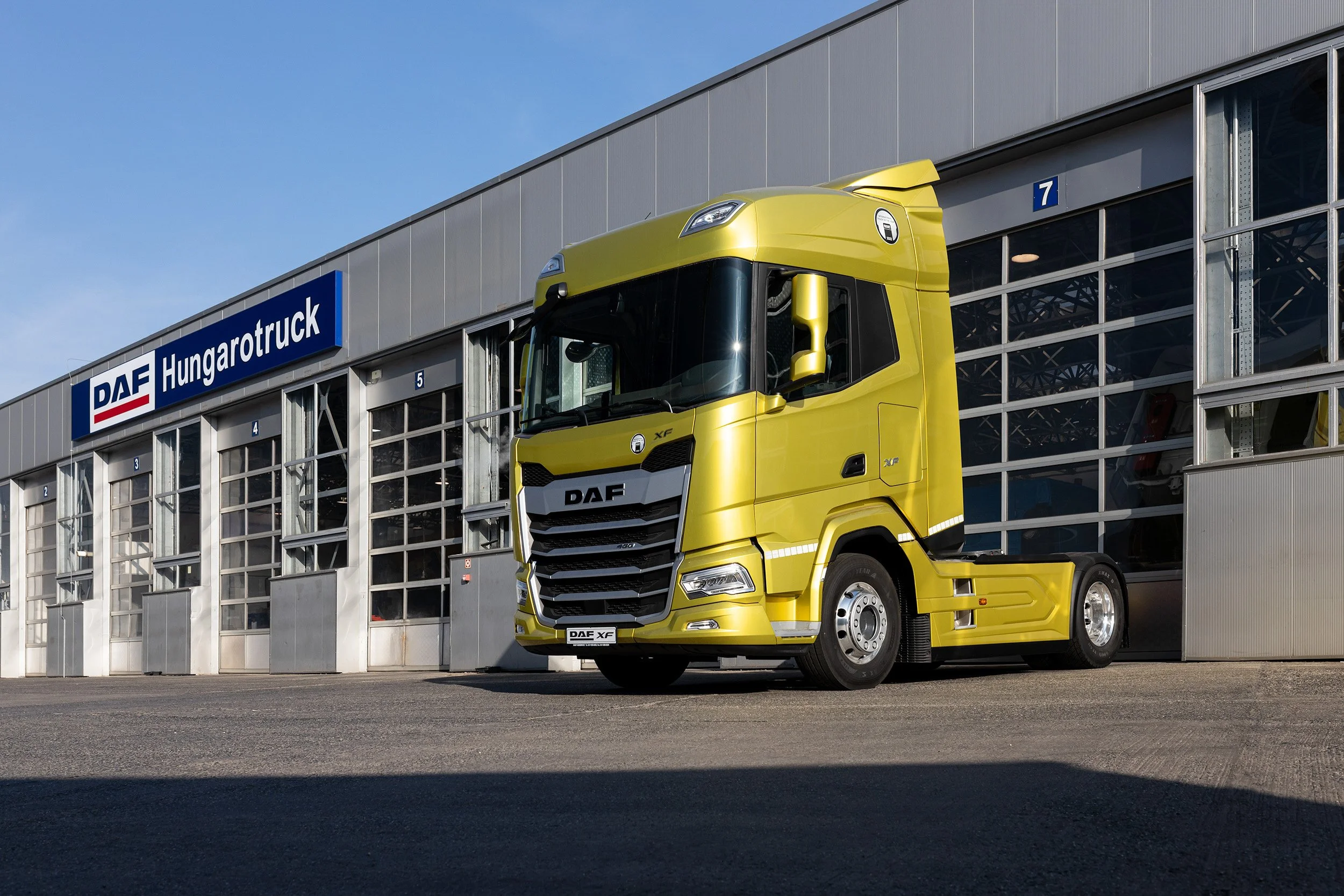 Yellow DAF XF truck parked outside a building with a 'DAF Hungarotruck' sign.
