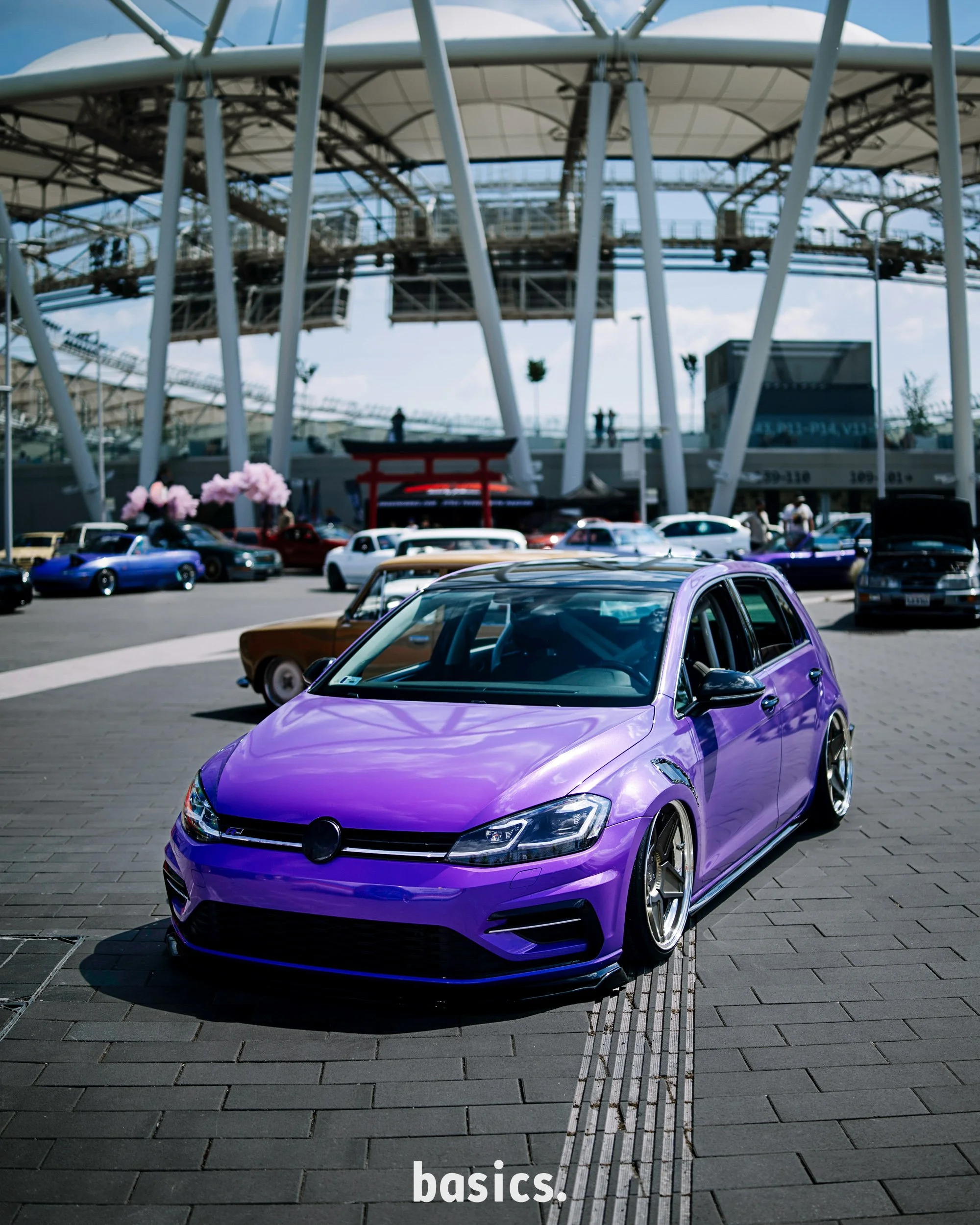 Lila Volkswagen golf mk7 gti a nemzeti atlétikai központ stadionnal a háttérben fotózva a Basics 2026 rendezvényen