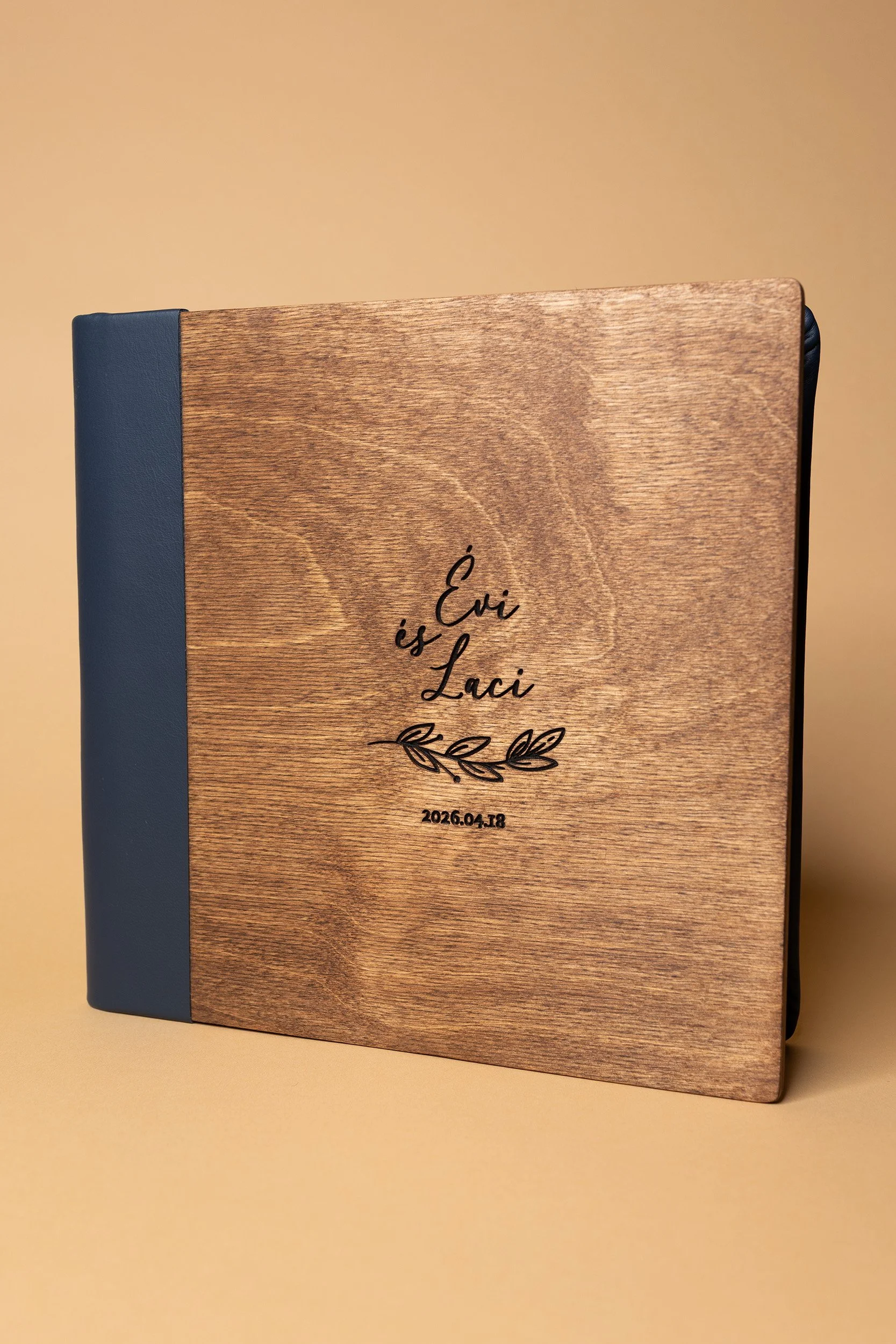 A wooden guestbook with the inscription 'Évi is Laci' and a date, resting on a light yellow surface with a beige background.