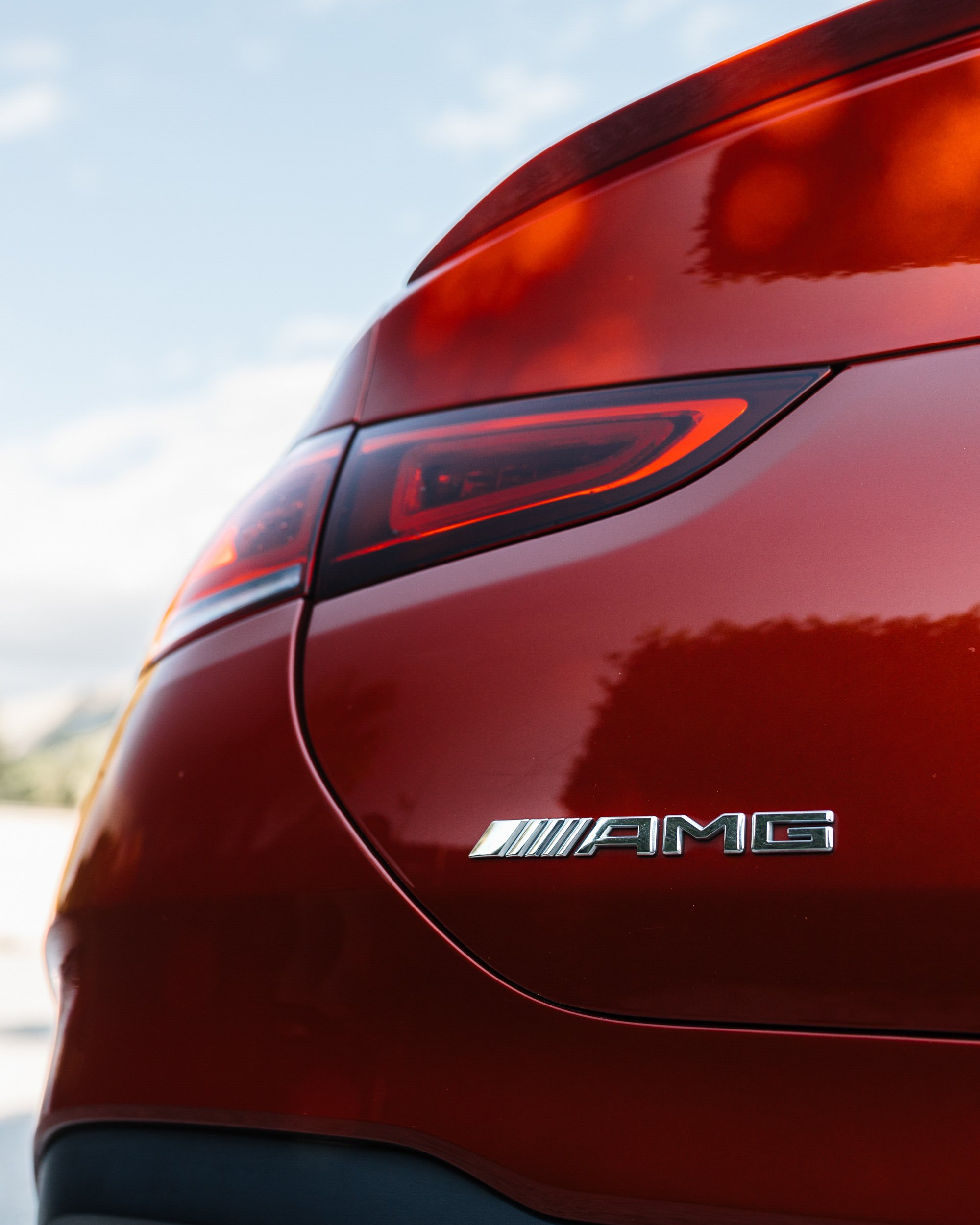 Close-up of the rear of a red Mercedes-Benz AMG vehicle, showing the AMG badge and part of the tail light.