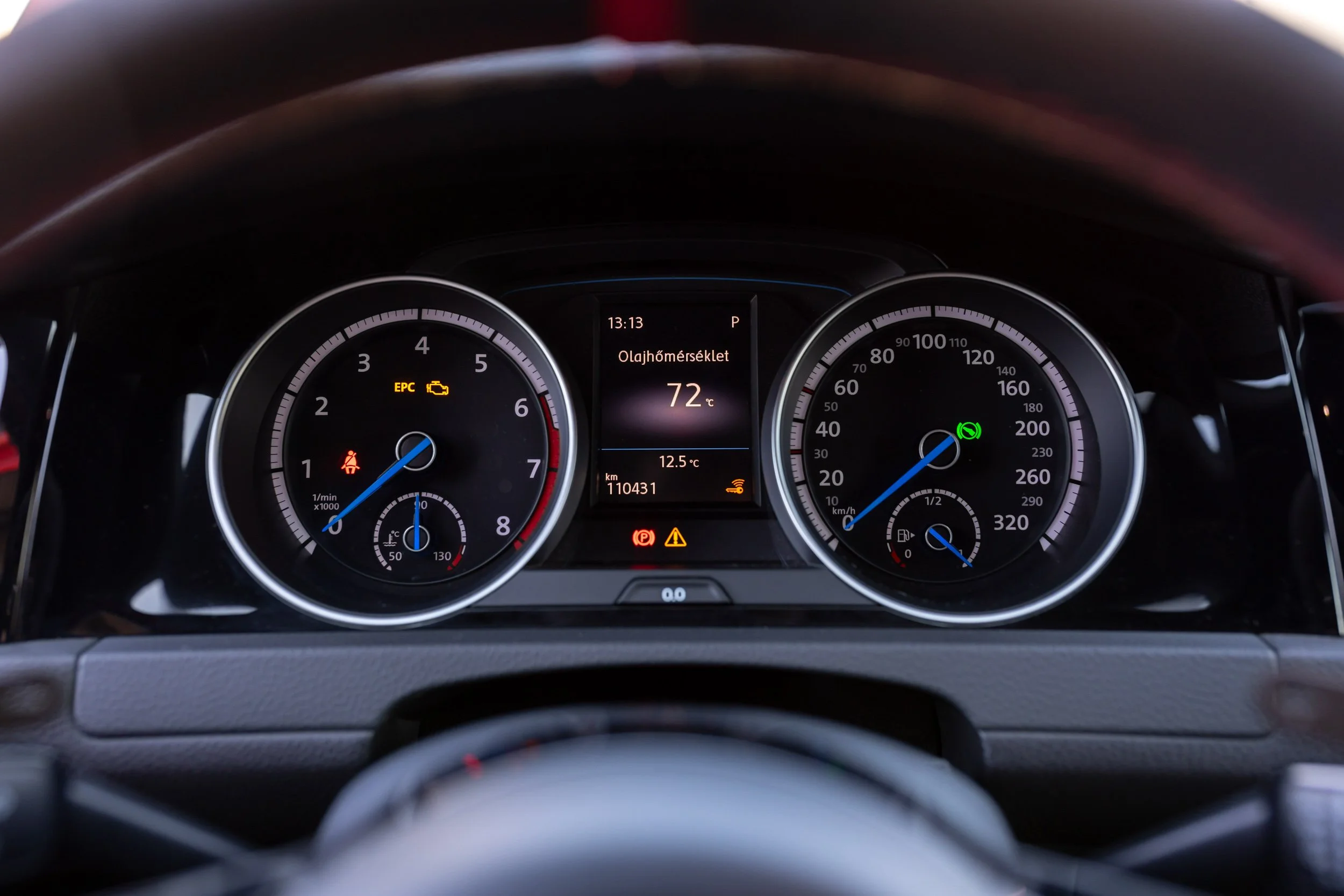 Close-up of a car dashboard showing various gauges and indicators, including the speedometer, tachometer, oil temperature, and warning lights.