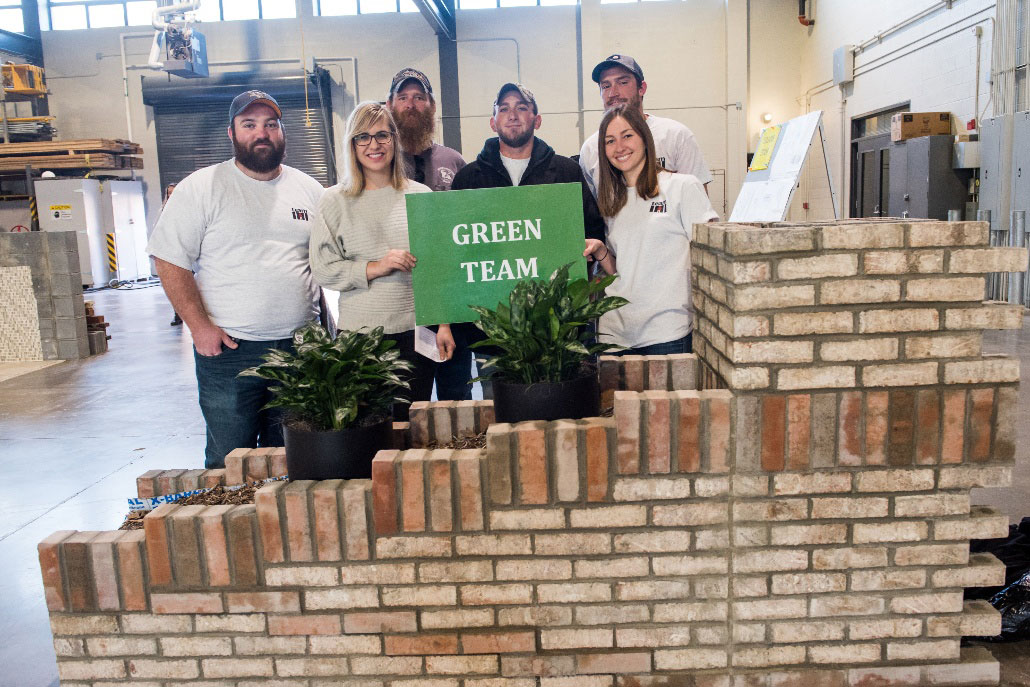 Kelsey Holmes with her fellow Green Team members with their finished project, which incorporated a custom drain solution to allow plans to grow between healing spaces in their center.