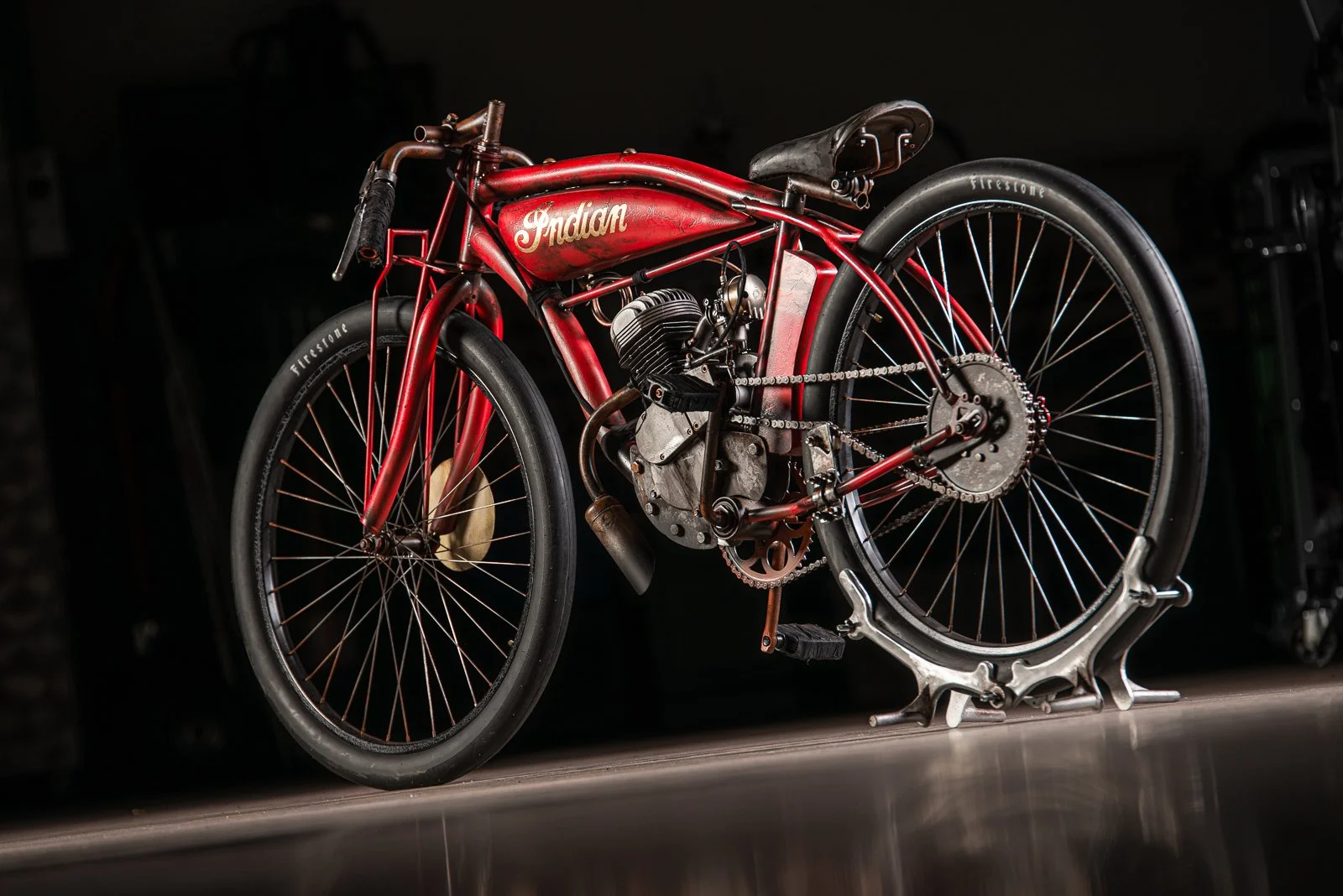 Vintage red Indian motorcycle with black wheels on a reflective surface