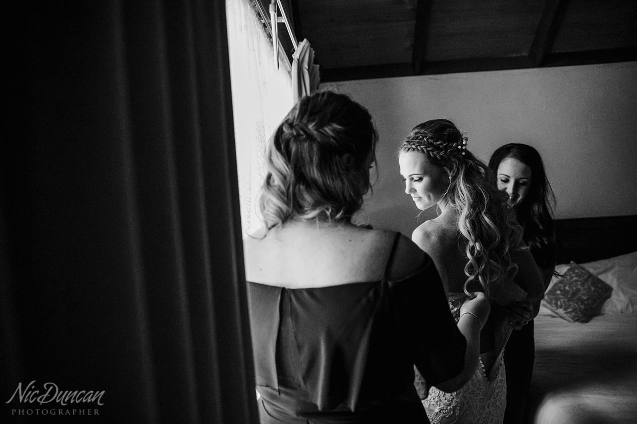 Bridesmaids helping the bride with her dress