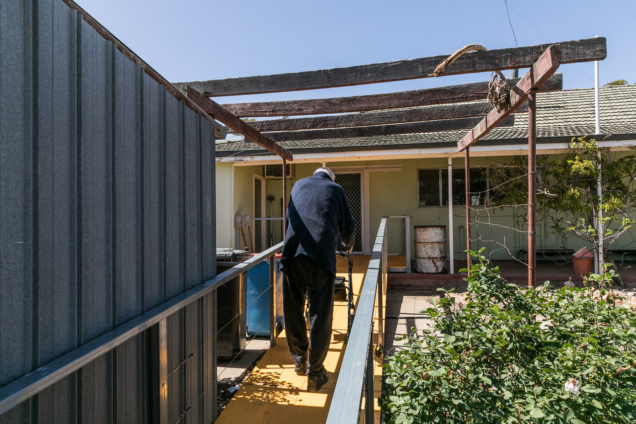 Elderly man with his frame, walking up the ramp to his front door