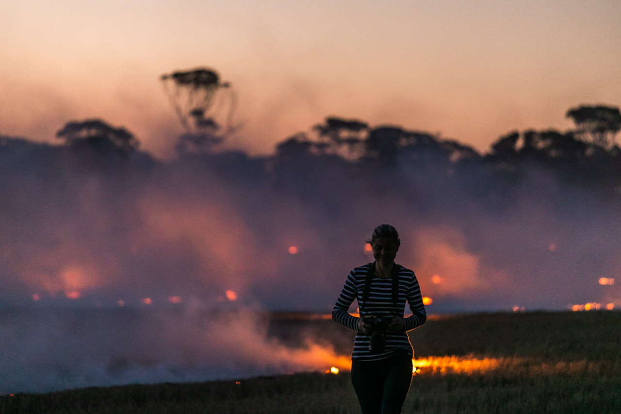 Silhouette of a person again the flames, smoke and salmon gums during windrow burning in Bruce Rock in WA's Wheatbelt