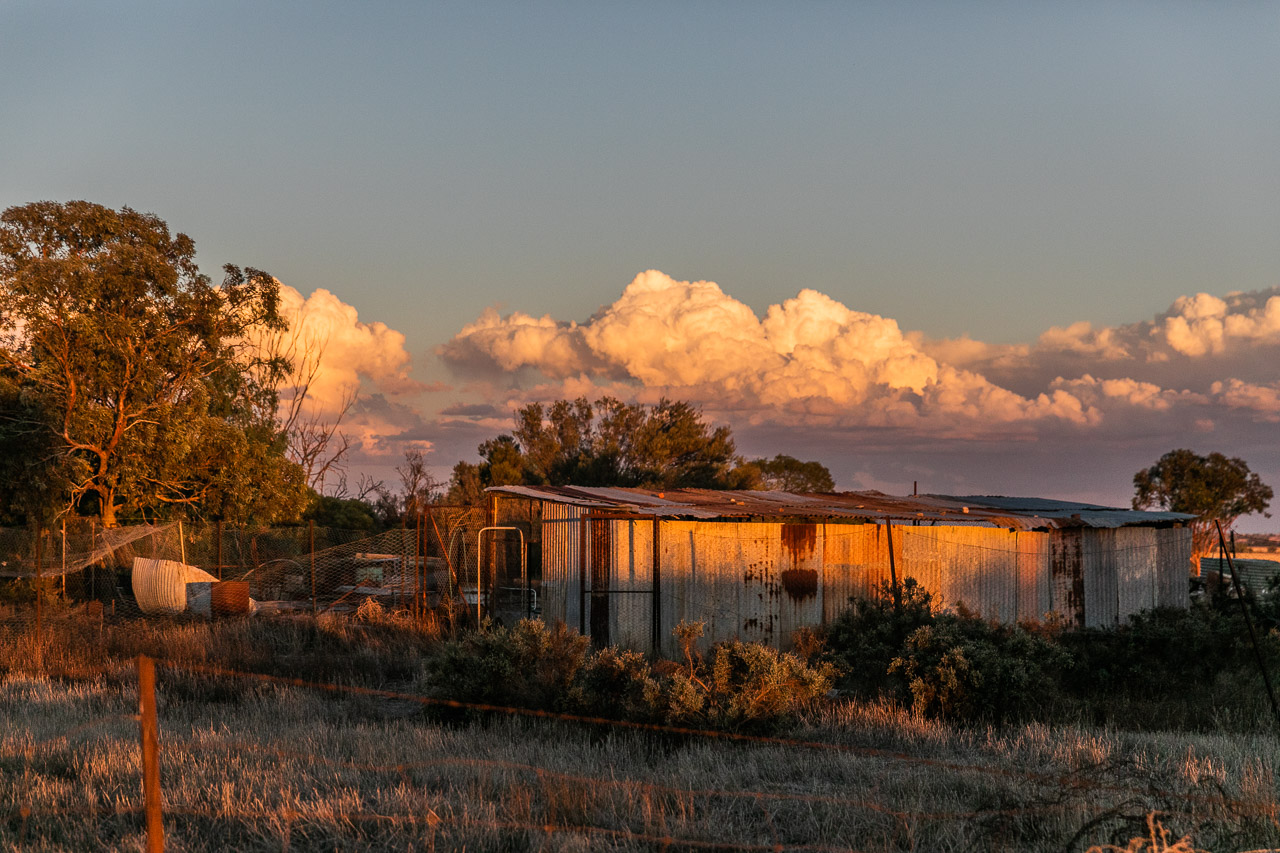 Old rusty farm sheds at sunset with storm clouds forming