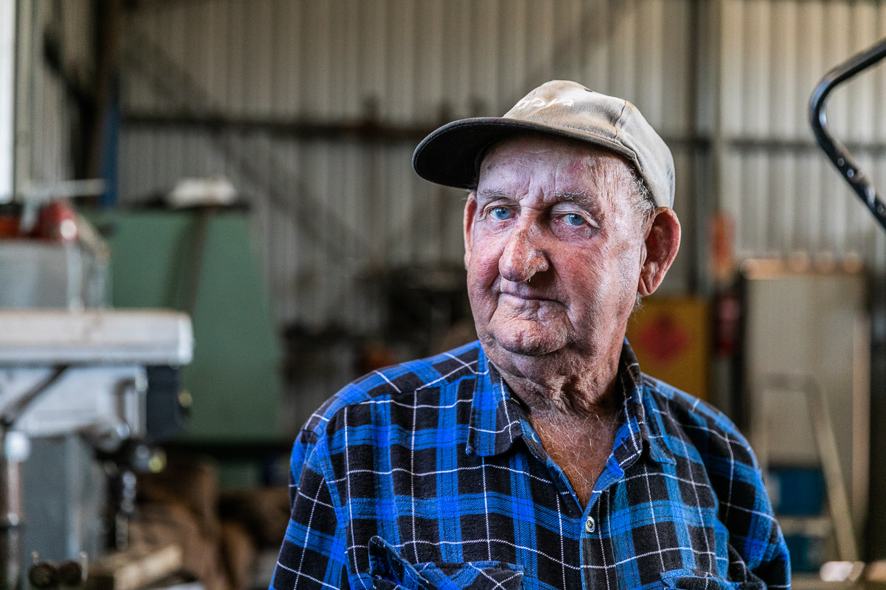 Old man in plaid shirt and baseball cap in his shed