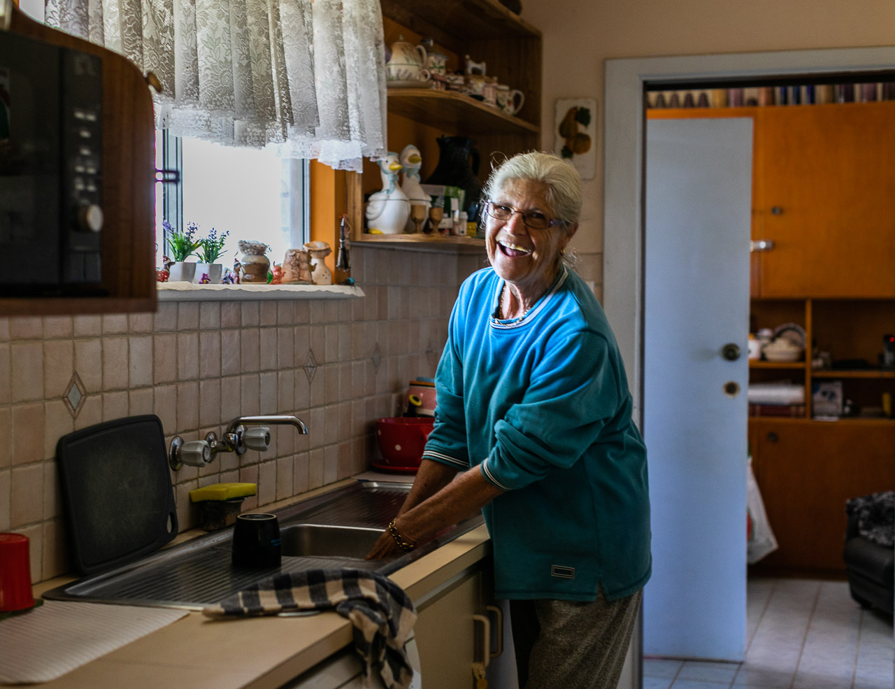 Elderly woman washing up in the kitchen