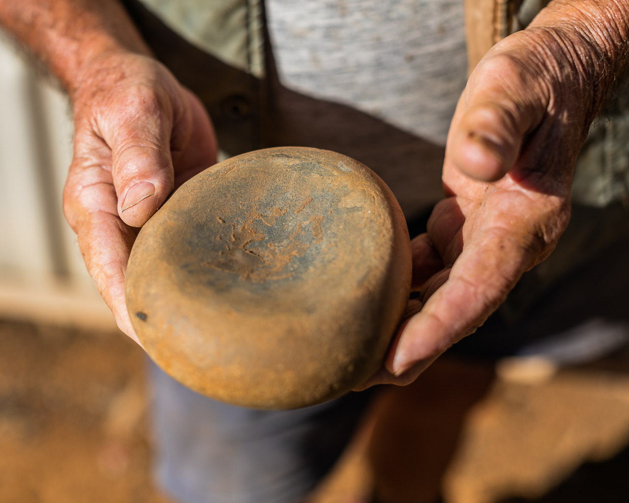 Aboriginal grind stone held in an old man's hands