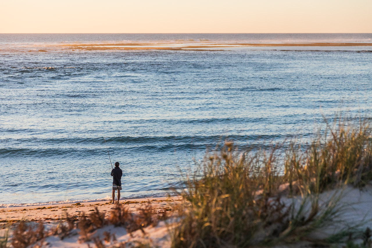 Lone fisherman at sunset on the beach