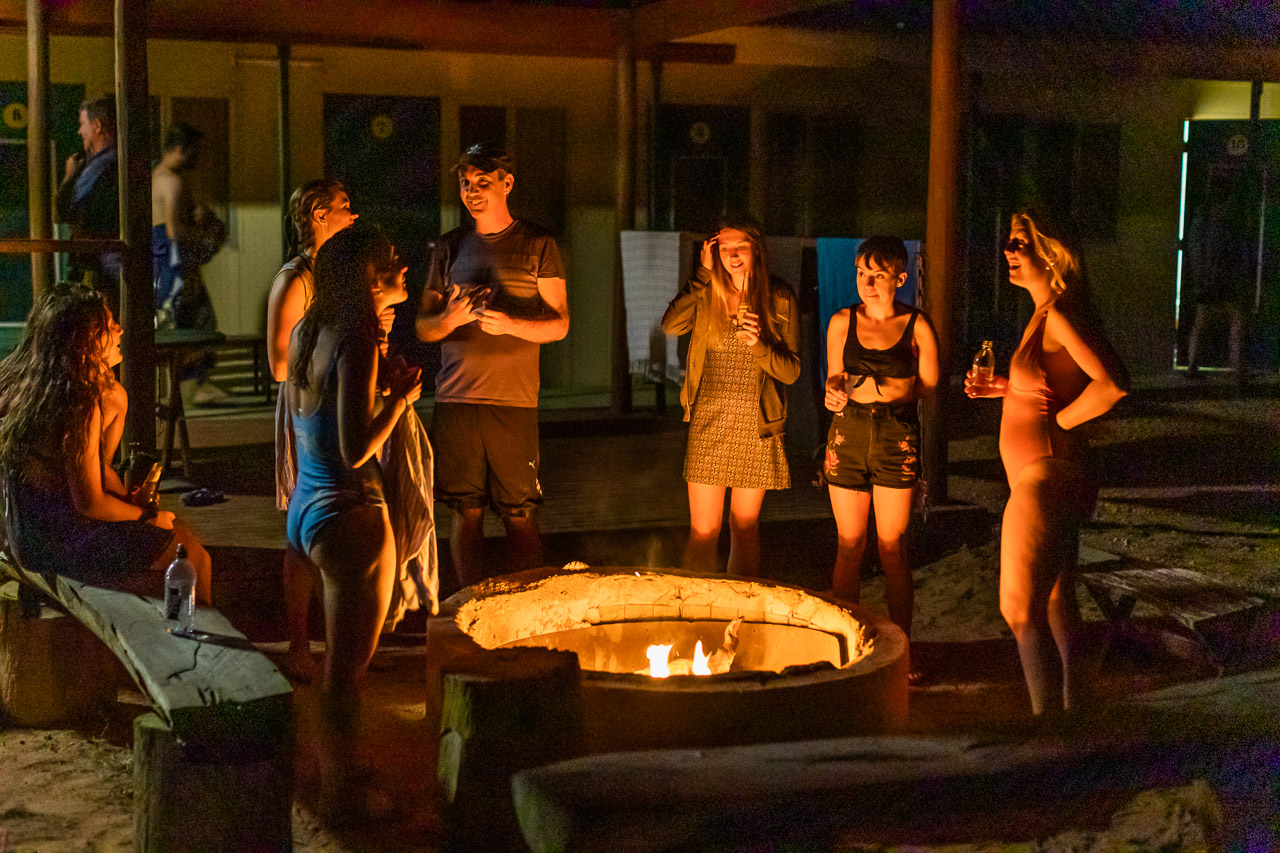 Backpackers chatting and drinking around the roaring camp fire at Warroora Station's shearers quarters