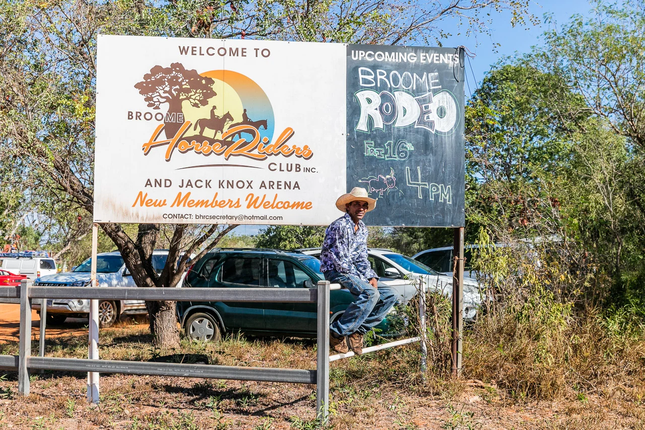 Cowboy sitting on the fence near the Broome Rodeo sign