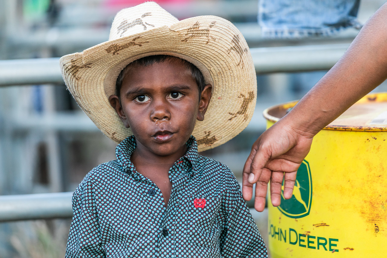 Young Aboriginal boy in a cowboy hat with a yellow and green barrel - Broome Rodeo 2019