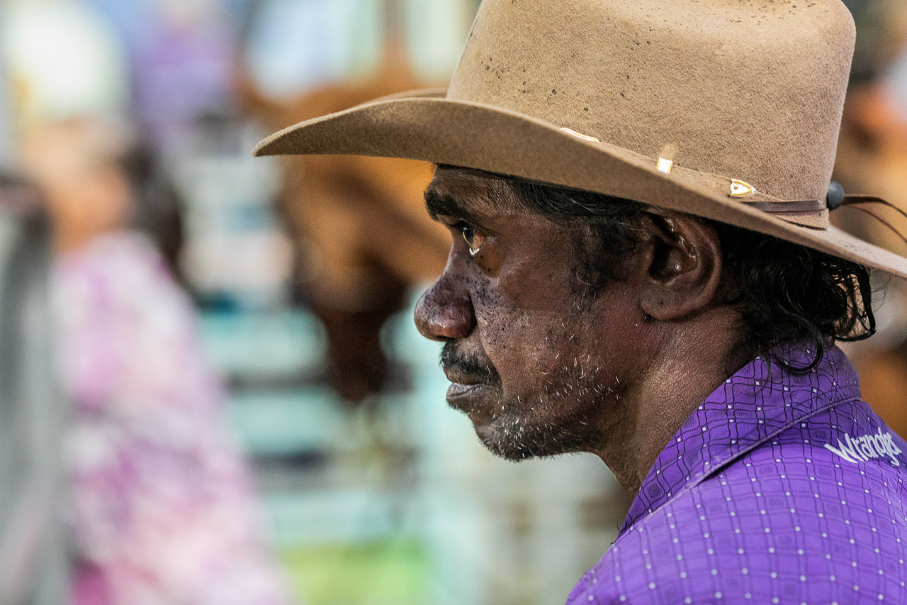 Profile portrait of an Aboriginal man wearing a cowboy hat and purple shirt