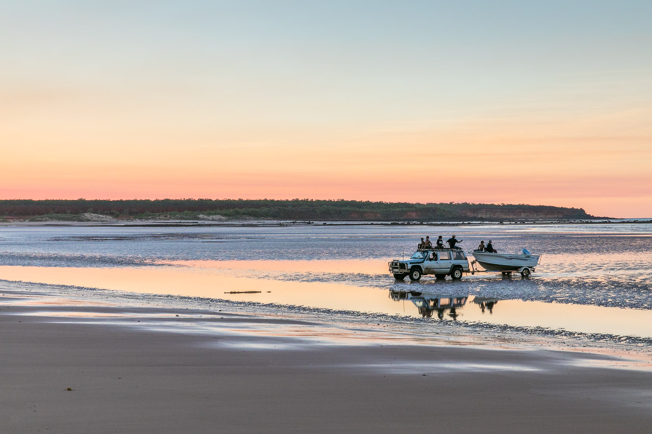 Toyota landcruiser towing a boat on the sand flats at low tide on the Dampier Peninsula at sunset.
