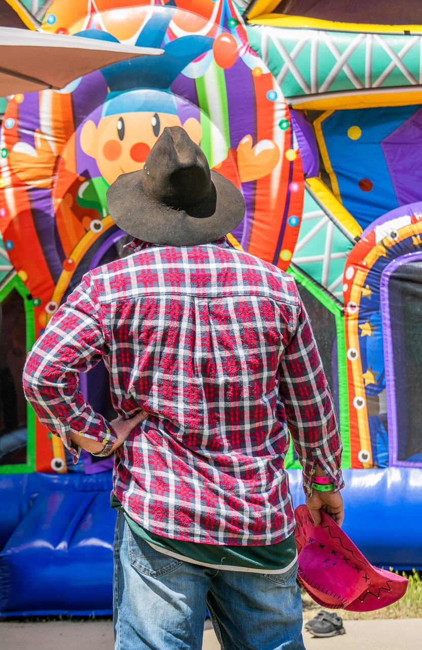 Cowboy Dad patiently waiting for cowgirl daughter to finish on the bouncy castle.