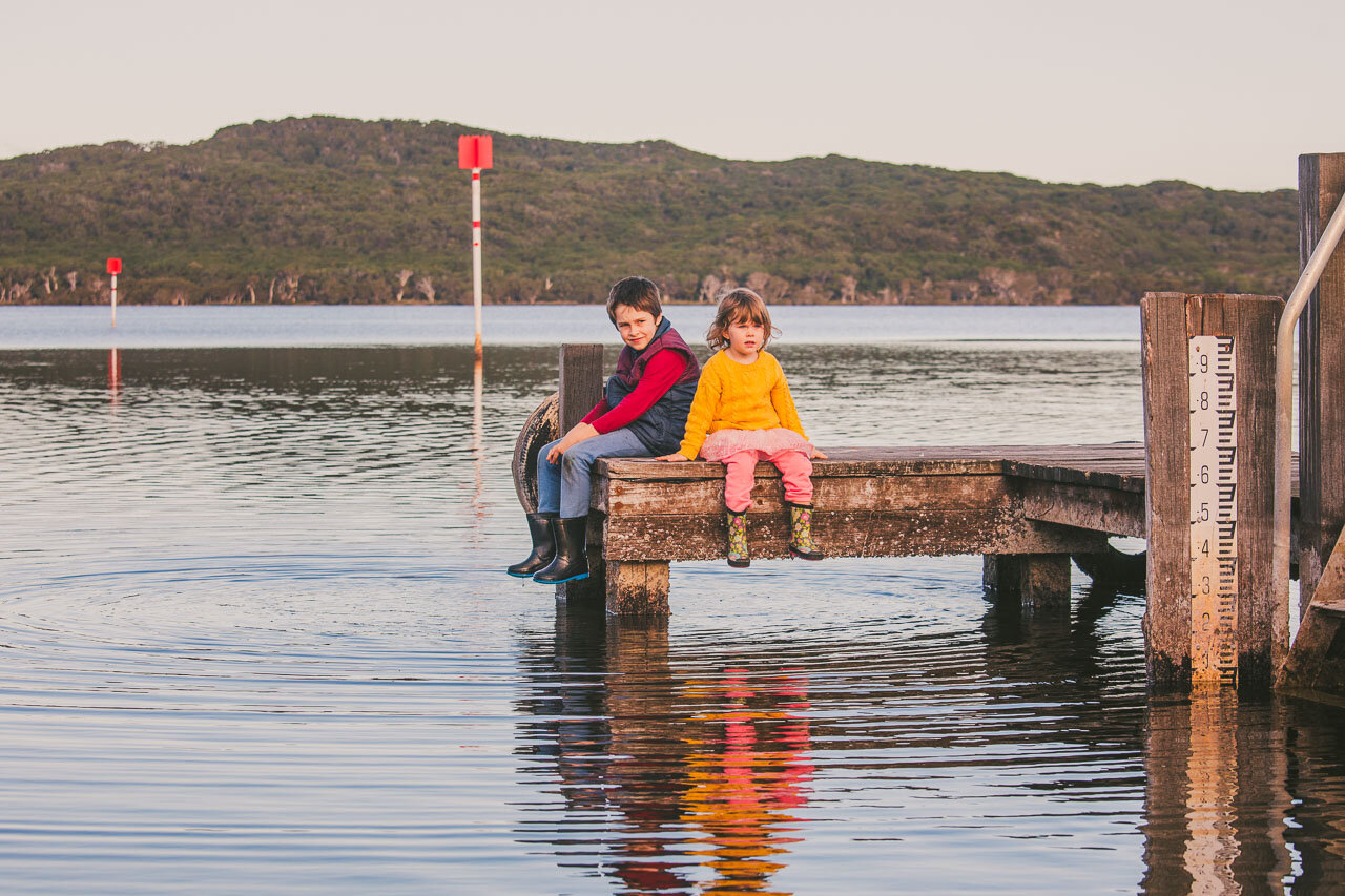 Brother and sister sitting on a jetty in Denmark, Western Australia