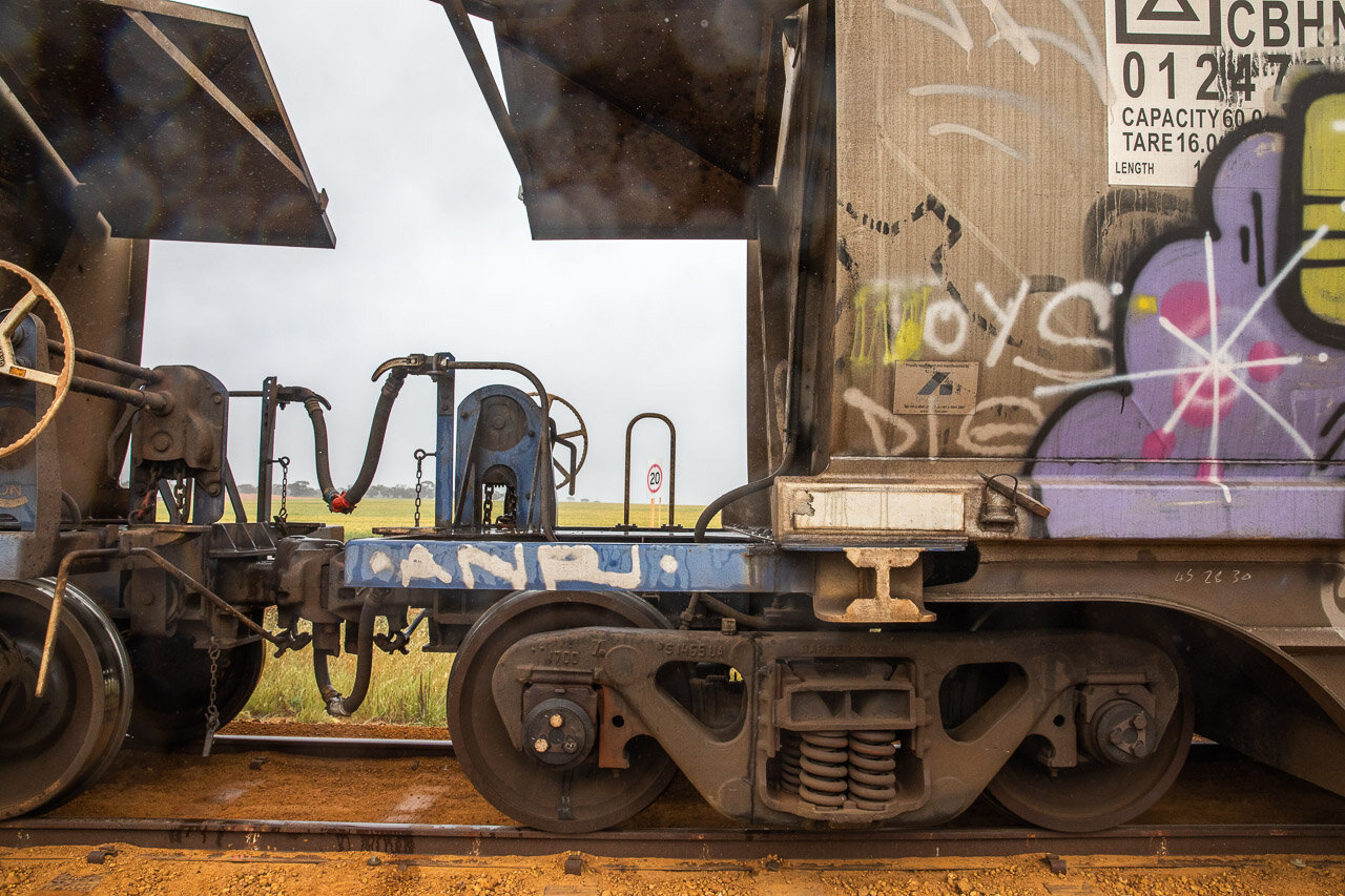 A CBH train carriage with graffiti and a paddock of wheat in the background