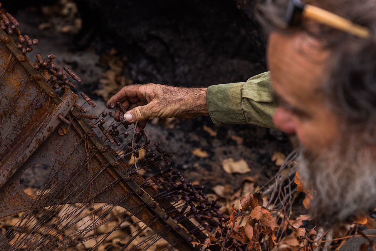 James Gentle inspects the burnt remains of an old piano after the Denmark bushfire