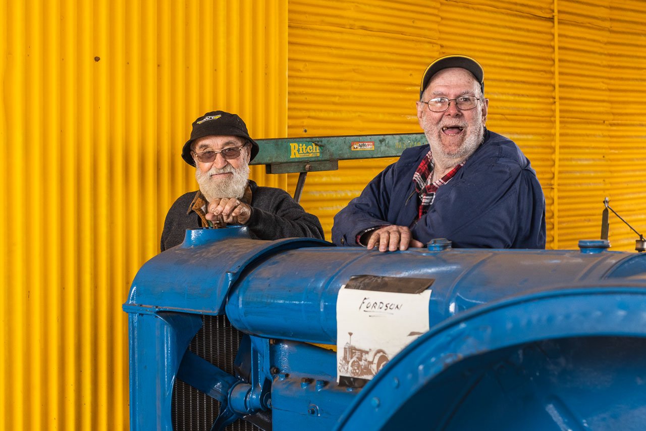 Two old blokes with a blue tractor and brightly painted wall