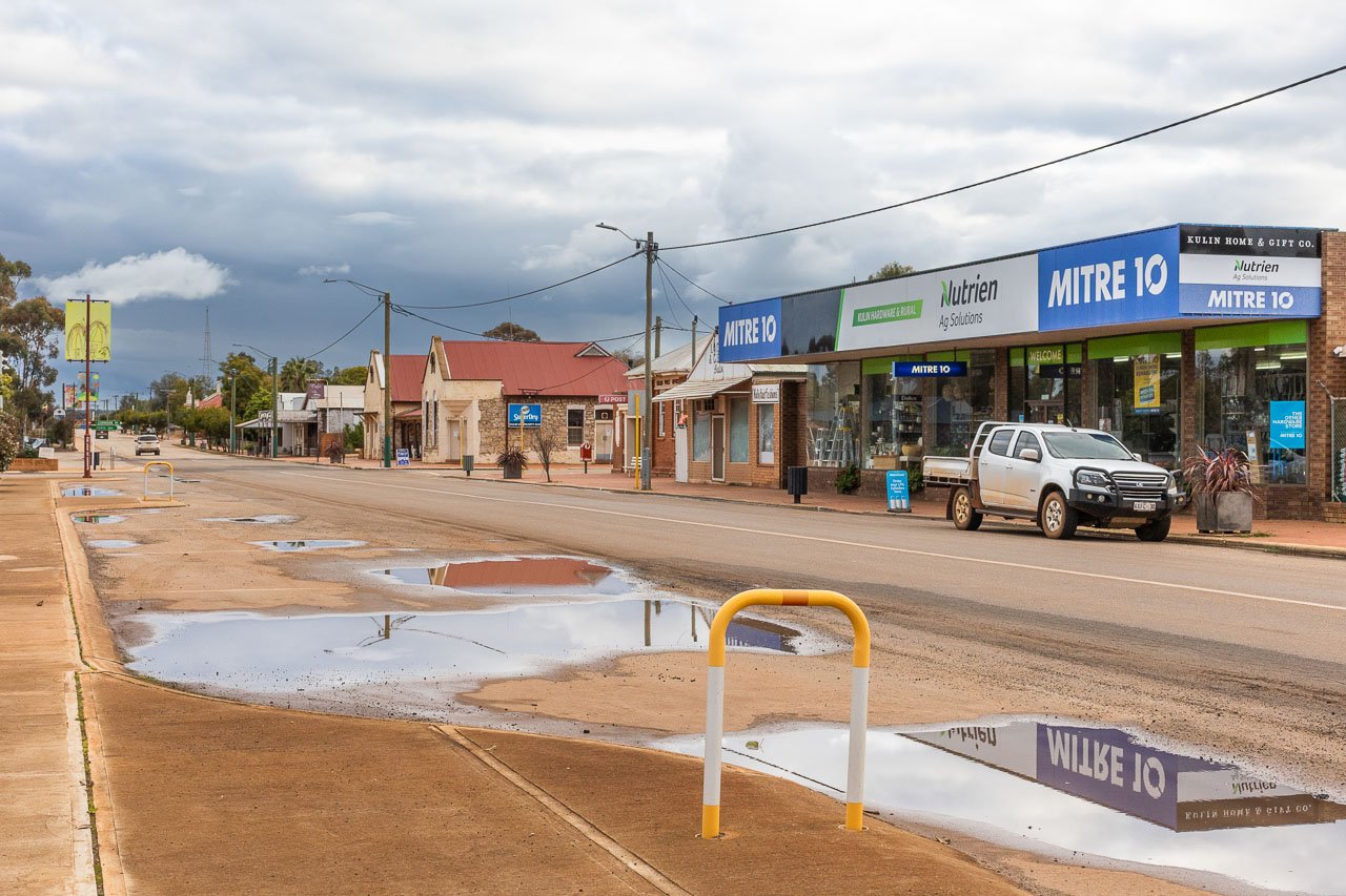 The main street of Kulin in Western Australia's Wheatbelt, with buildings reflected in a puddle