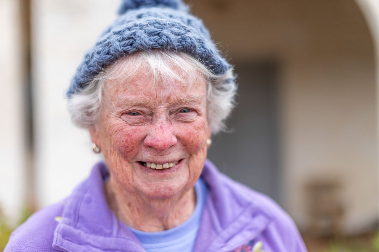 Elderly lady smiling with a blue knitted hat