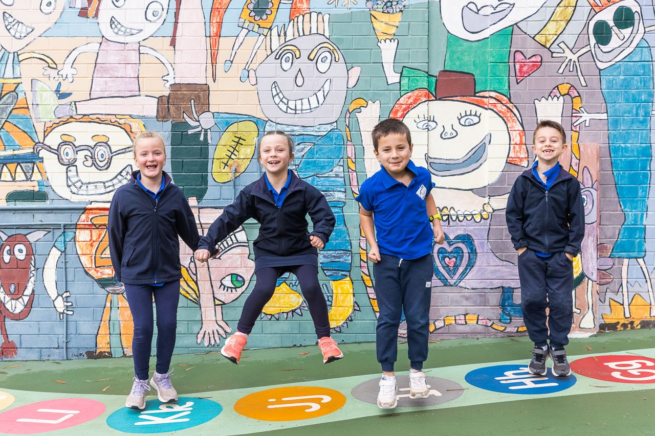 School children in their uniforms having fun in front of a brightly coloured mural on a wall