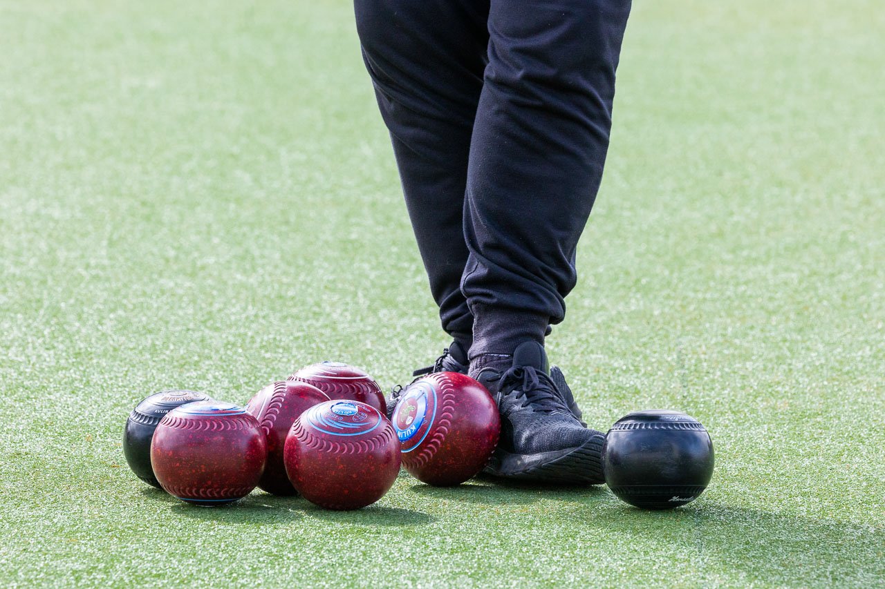 Close-up of lawn bowls and a person's feet
