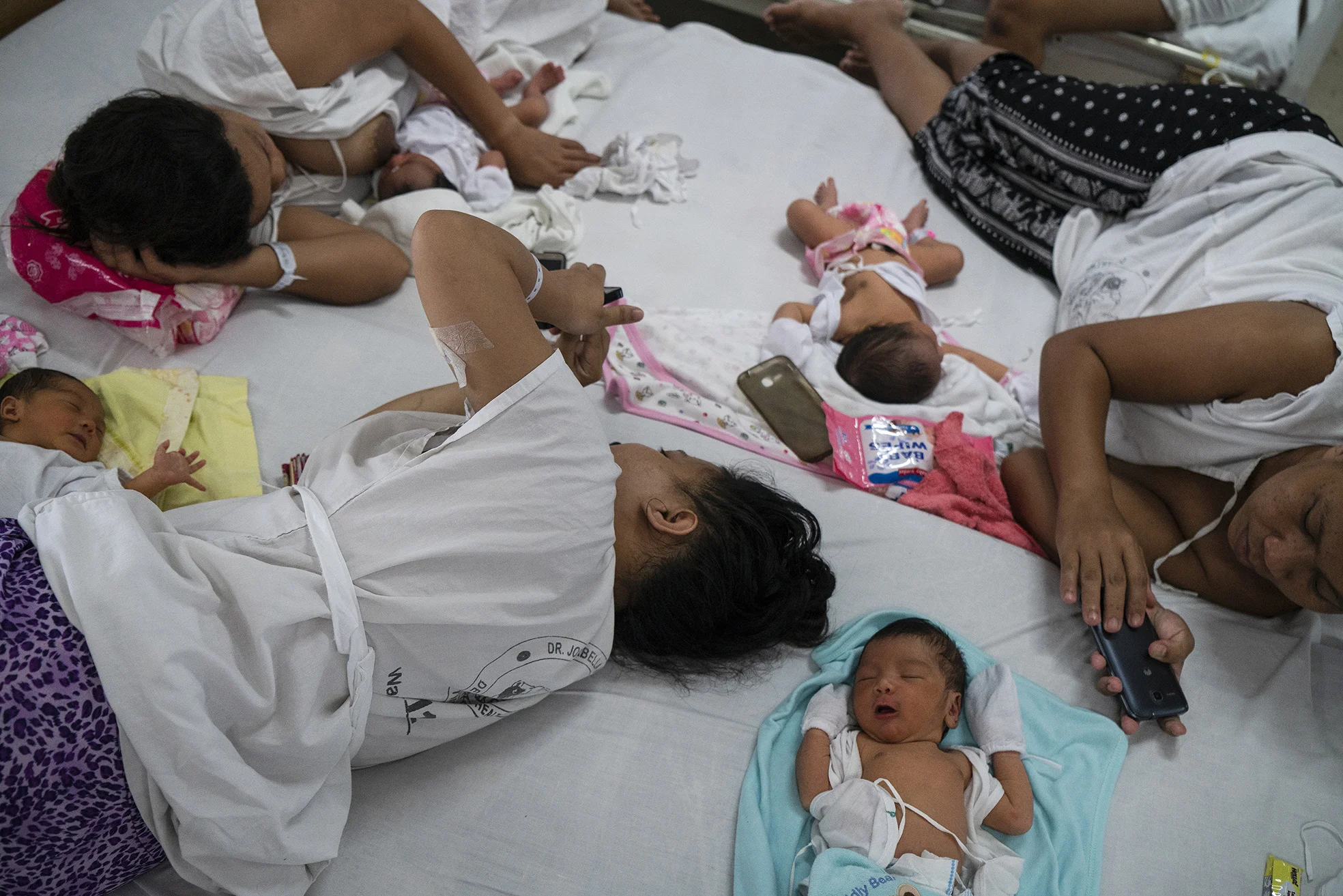 Newly given birth patients share a bed in Fabella Hospital in Manila on October 21, 2018. Dr. Jose Fabella Memorial Hospital is considered the busiest maternity hospital with an average of 60 births a day from the poorest patients in Manila and nearby provinces.