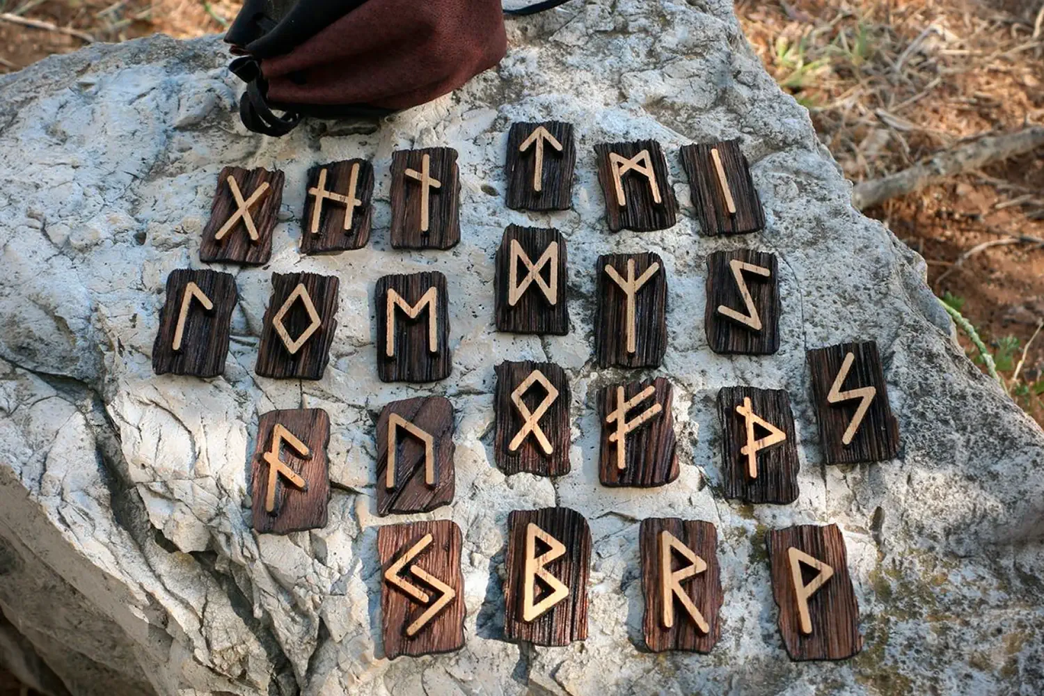 Wooden Elder Futhark rune set stored in a cloth pouch for symbolic study, meditation, and rune reading.