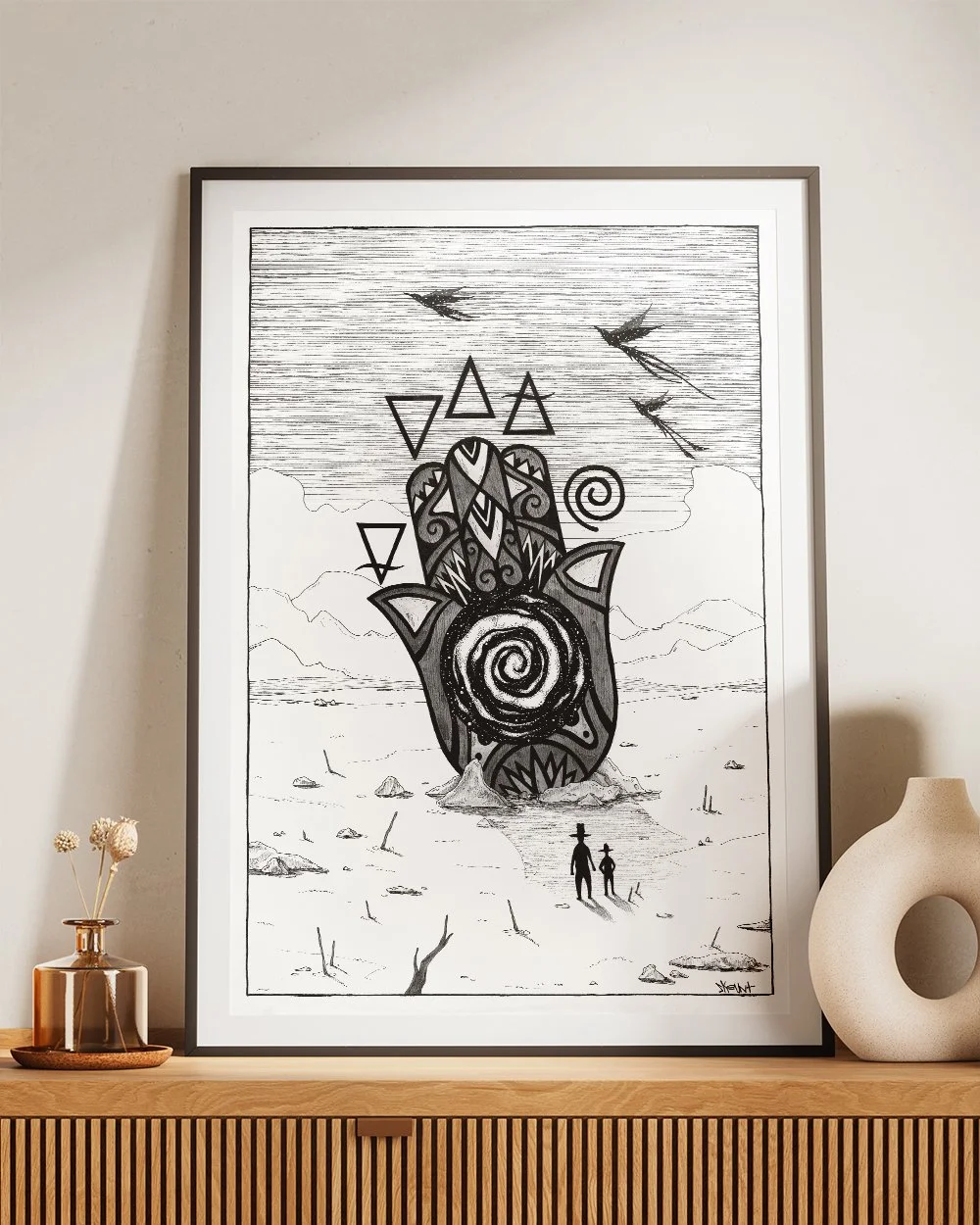 Framed artwork ‘The Secrets of Transformation’ by Skount displayed in a modern living room – symbolic ink illustration with Hamsa and alchemical elements.