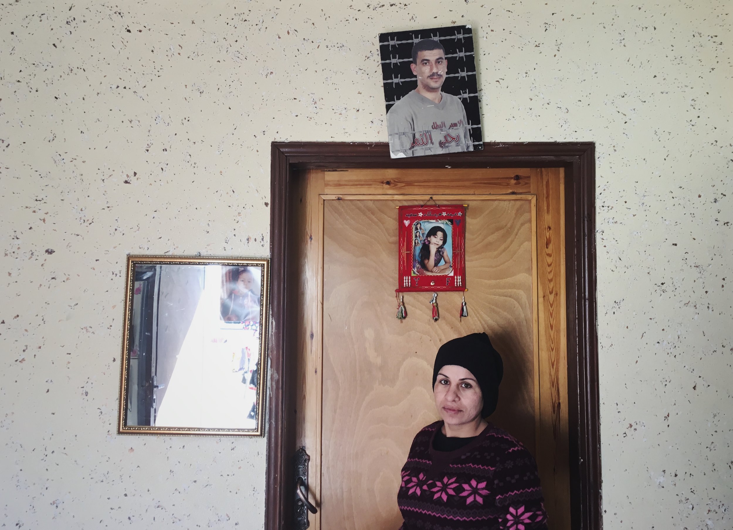  Sameera smuggled her husband's sperm from an Israeli prison. She's standing in her kitchen beneath a photo of her 11 year old daughter who died in a car crash and her husband who's been in prison for 14 years. Story published by Snap Judgment.&nbsp;