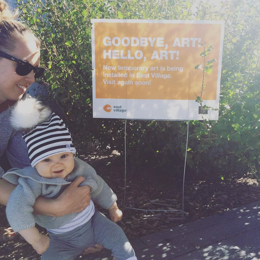 My wife and daughter beside signage announcing that the murals were about to go up.