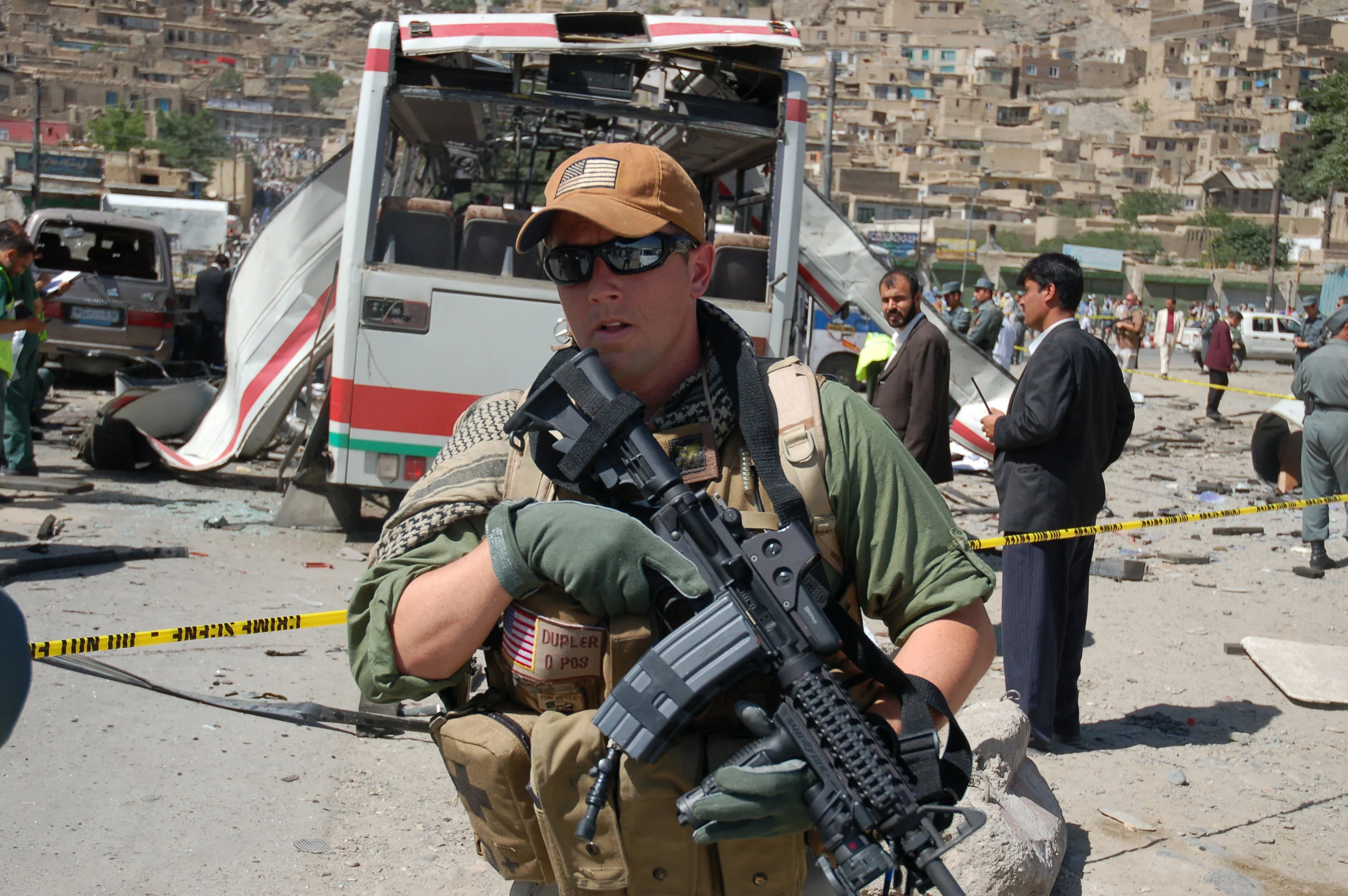 A US contractor guards the scene of a suicide attack on a bus carrying police recruits in central Kabul. At least 35 people were killed and 52 wounded. June 18, 2007.