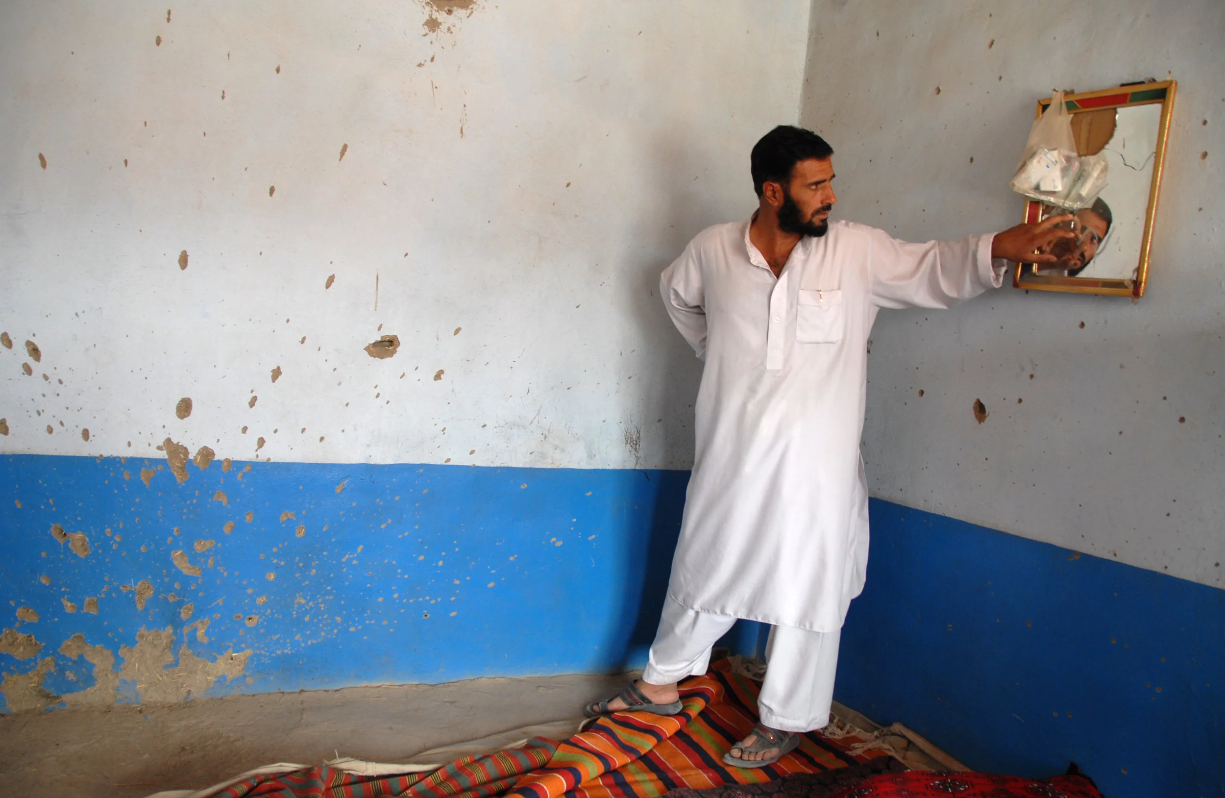 Aziz Azizi checks the house of his relatives after it was raided by Afghan and foreign troops. Among those killed were a 24-year-old man, the man's wife and their two sons, aged around one and two. Kabul, September 2008.