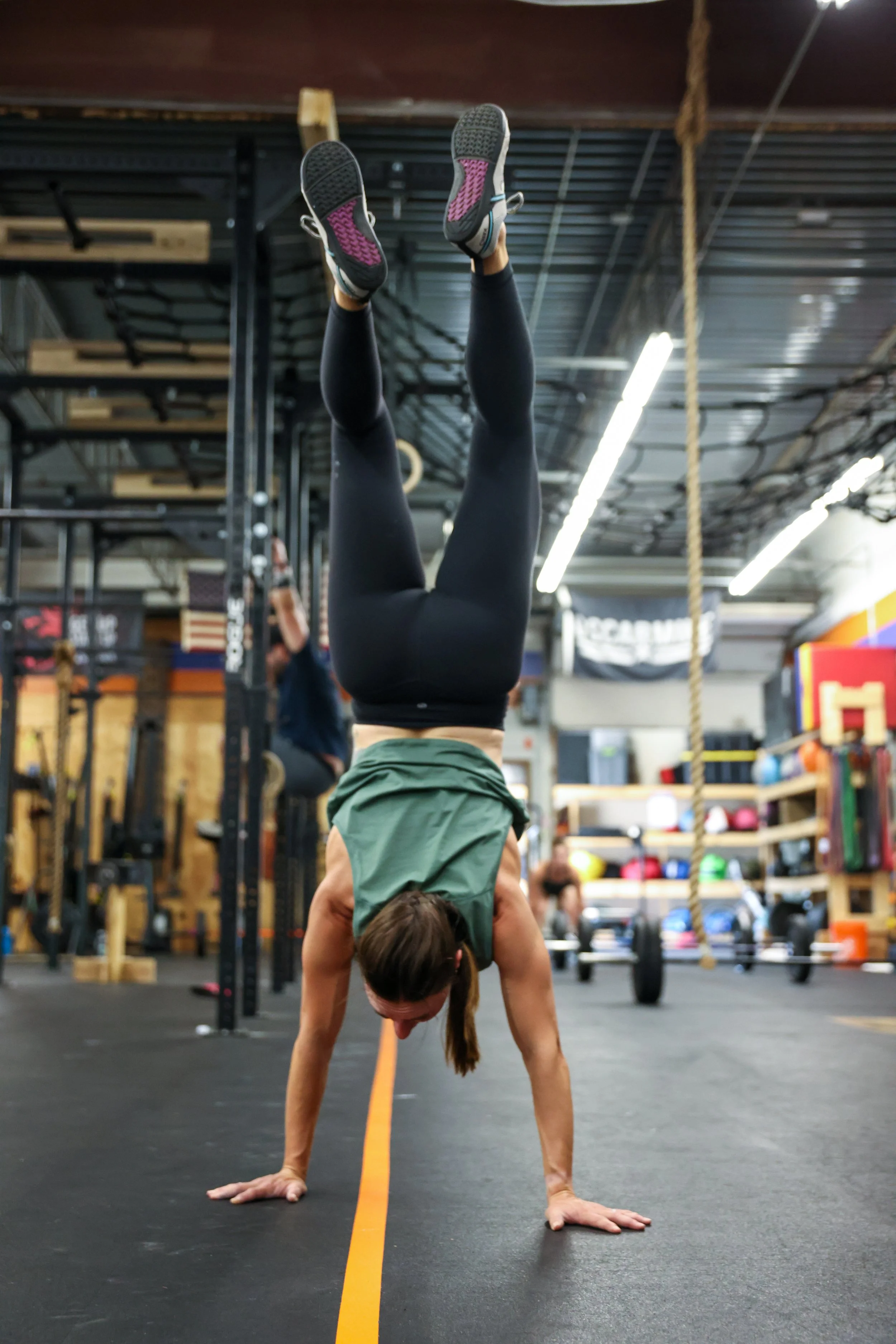 Photo of a woman in a CrossFit gym handstand walking