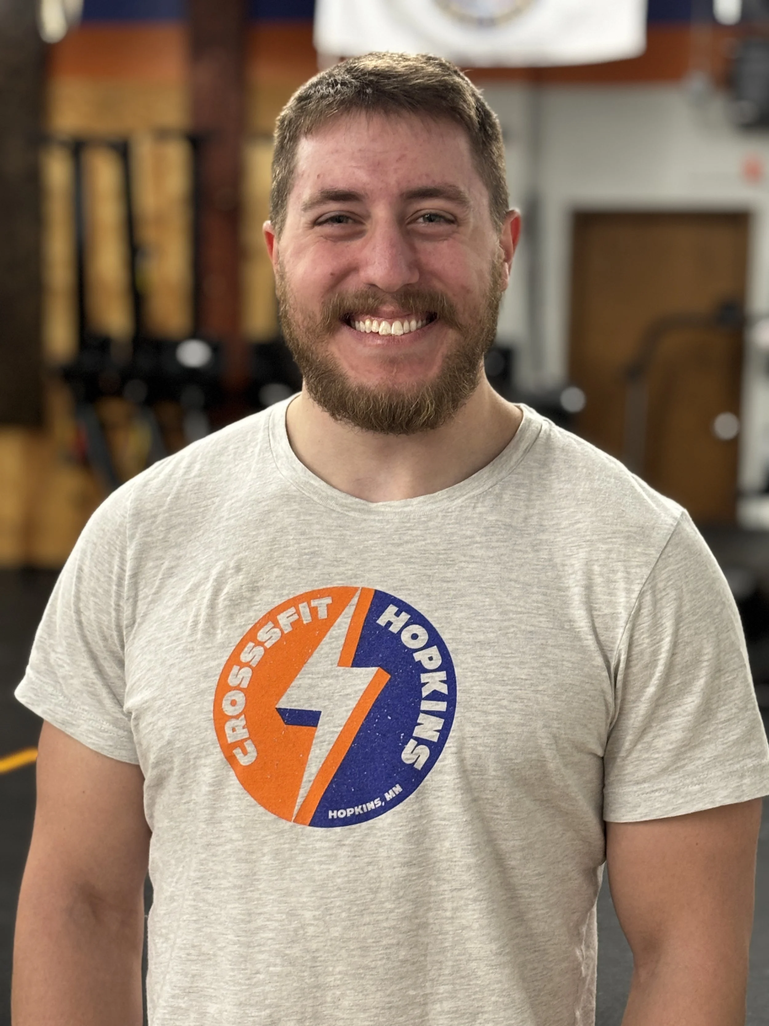 Headshot of a man in a gym wearing a gym branded t-shirt