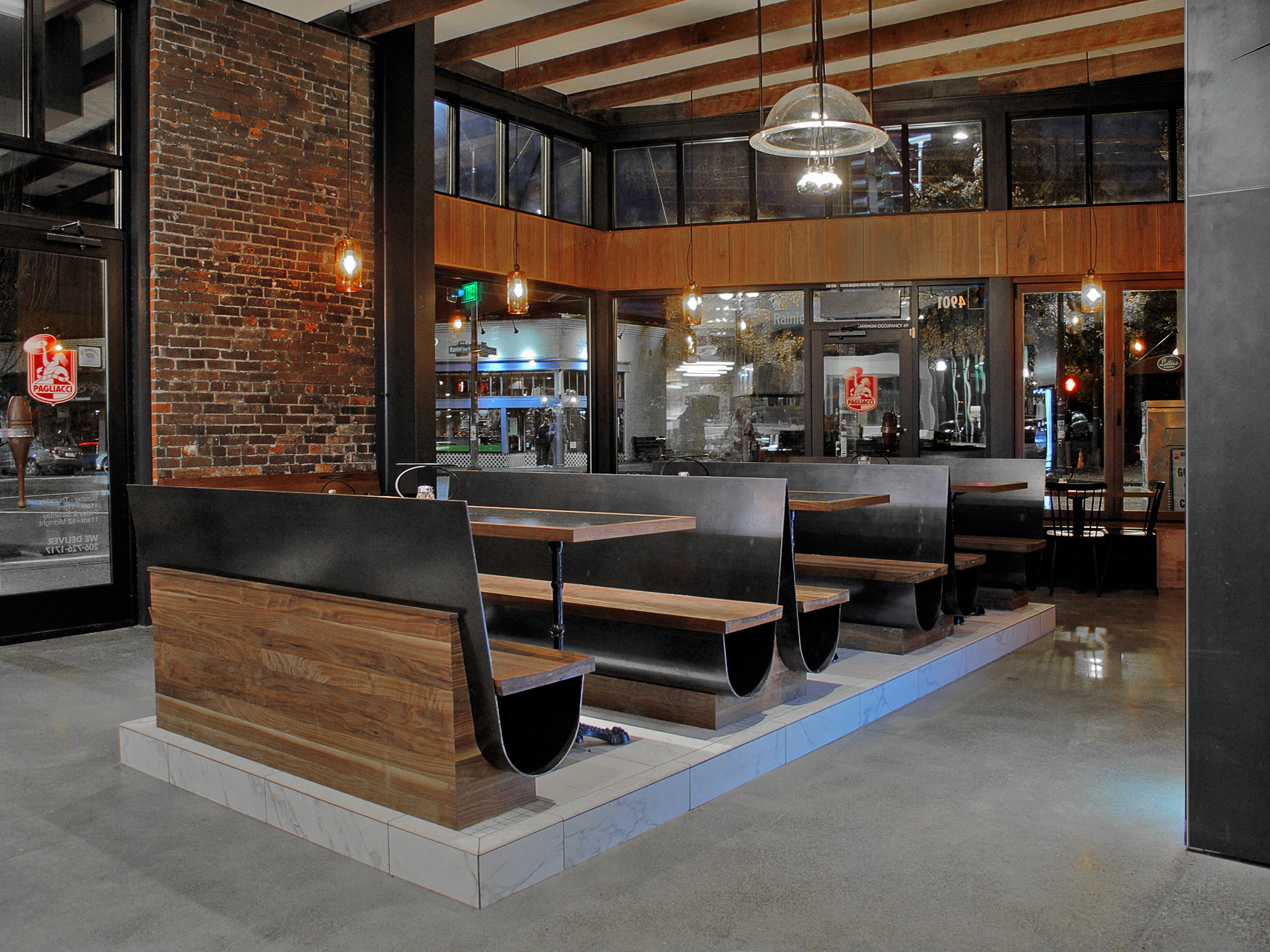 Wood was added above the storefront system to complement the original brick walls and concrete floors of the Hastings Building . Drywall ceilings were painted white and the window frames black to let brick be the protagonist in the space. The windows provide natural lighting during the daytime and LEDs in the ceiling create atmosphere at night.
