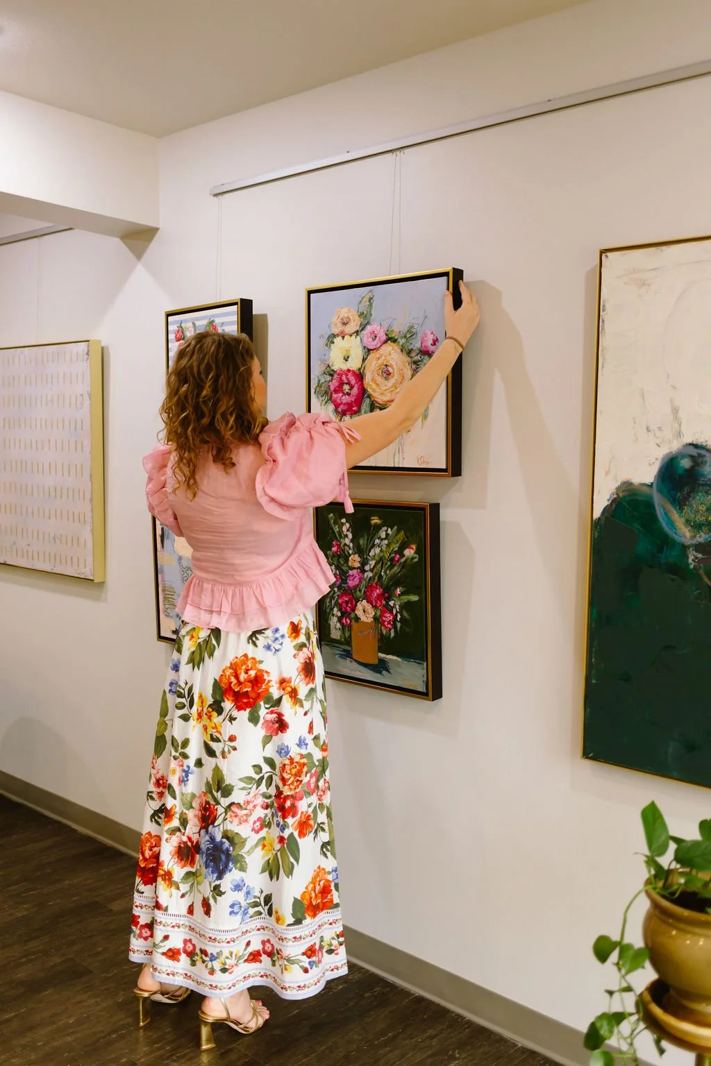 Artist straightening floral painting in gallery