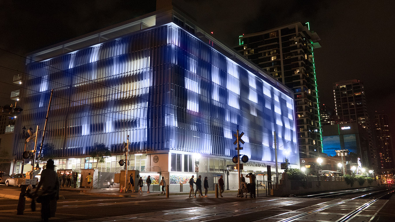 A large parking garage with vertical panels glows with a soft blue light, displaying a nature-inspired animation.