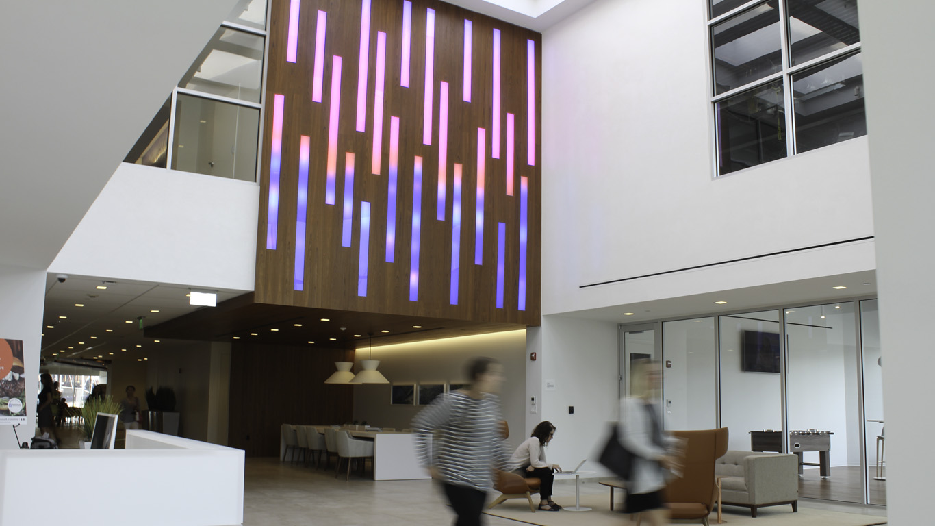 An indoor lighting installation in an upscale building lobby. Rectangles of light inlayed into wood show the colors of the sunset and ocean.